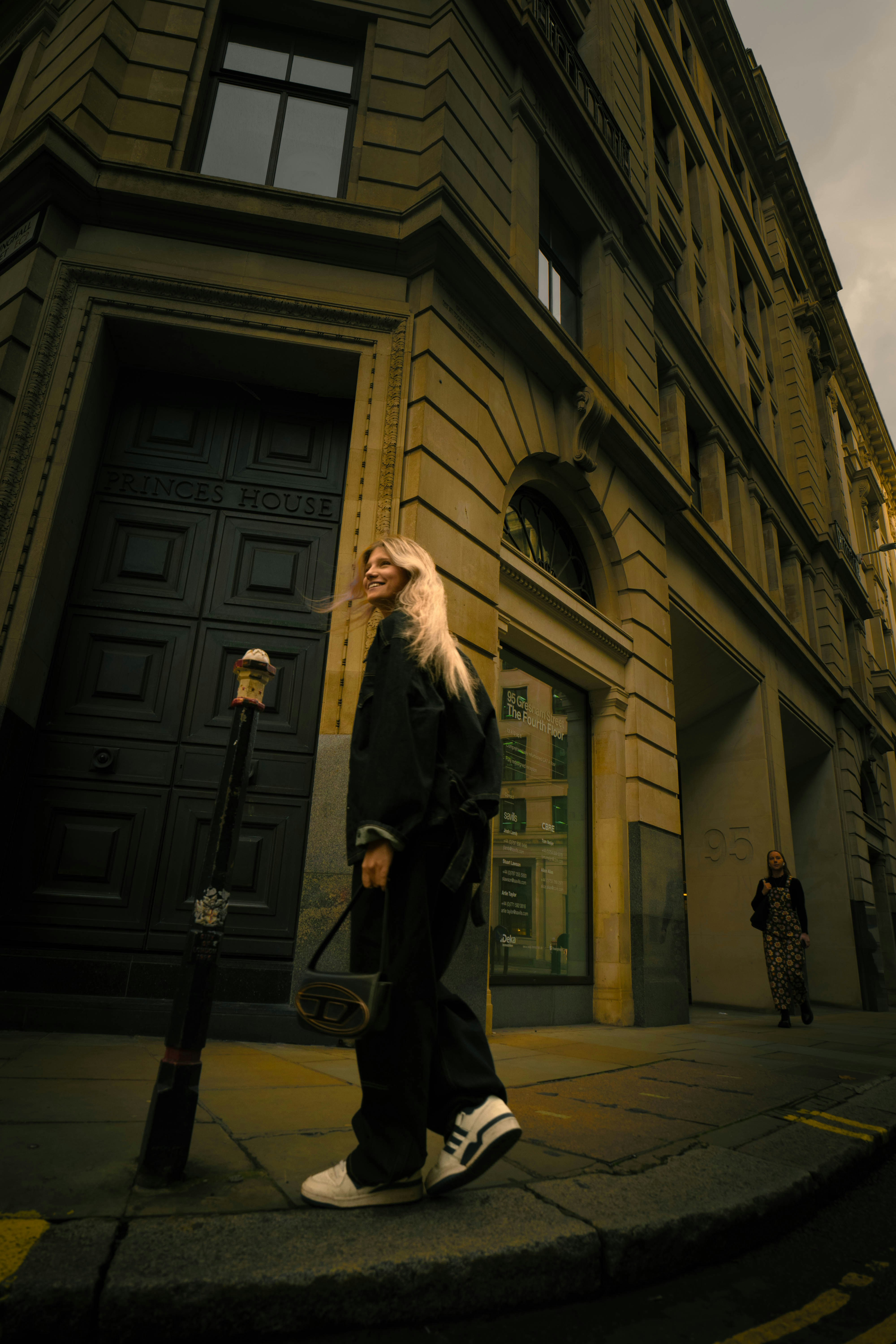 Una mujer caminando por una calle junto a un edificio alto