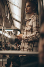 A man standing on a train holding a cell phone