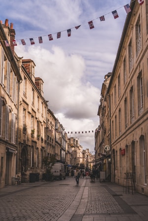 A cobblestone street lined with buildings and flags