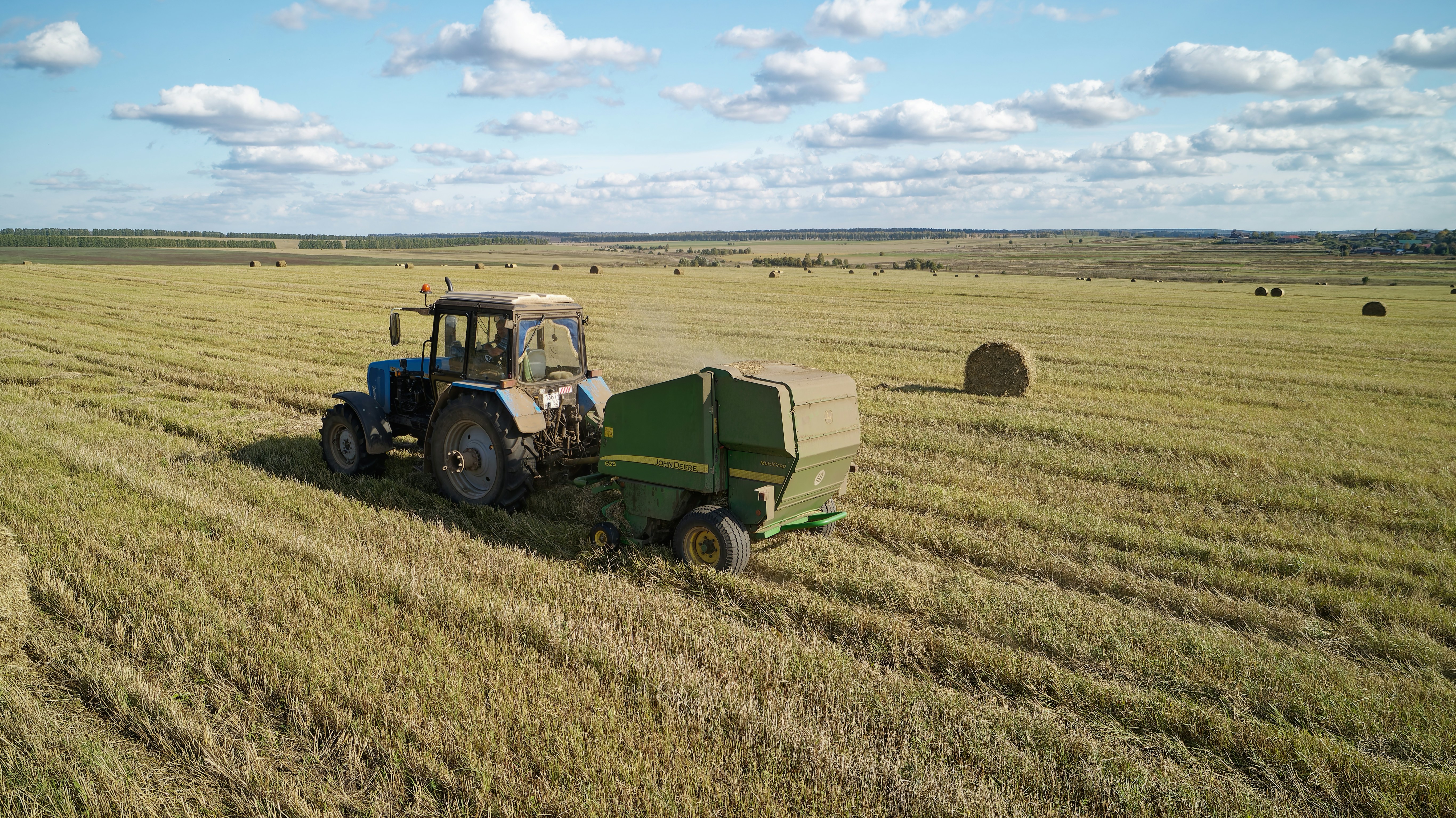 A tractor in a field with bales of hay