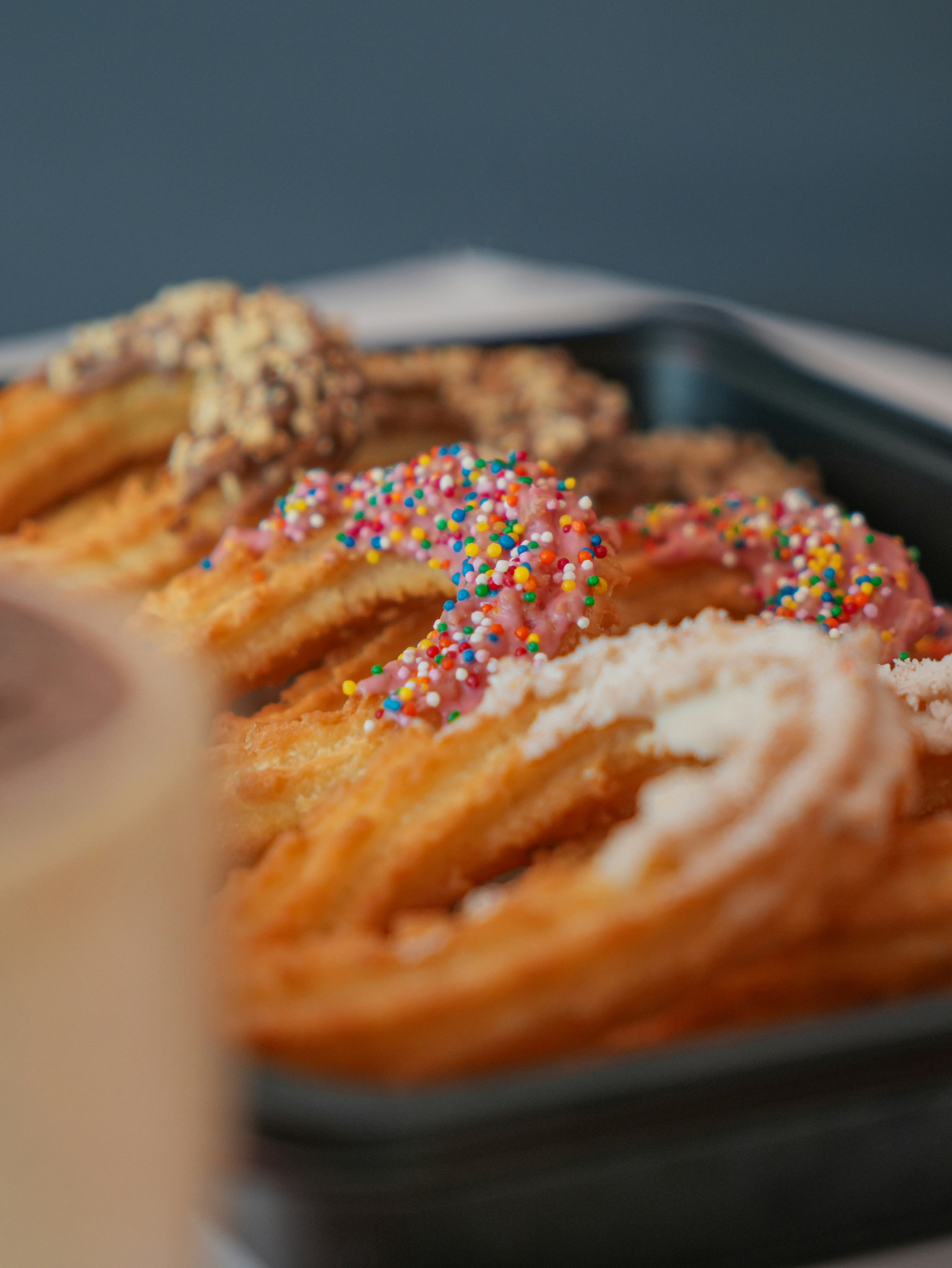 A tray of donuts with sprinkles and a cup of coffee