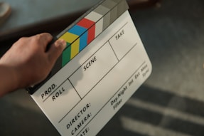 Claquete de cinema sendo segurada por cineasta em set de filmagem – produção audiovisual