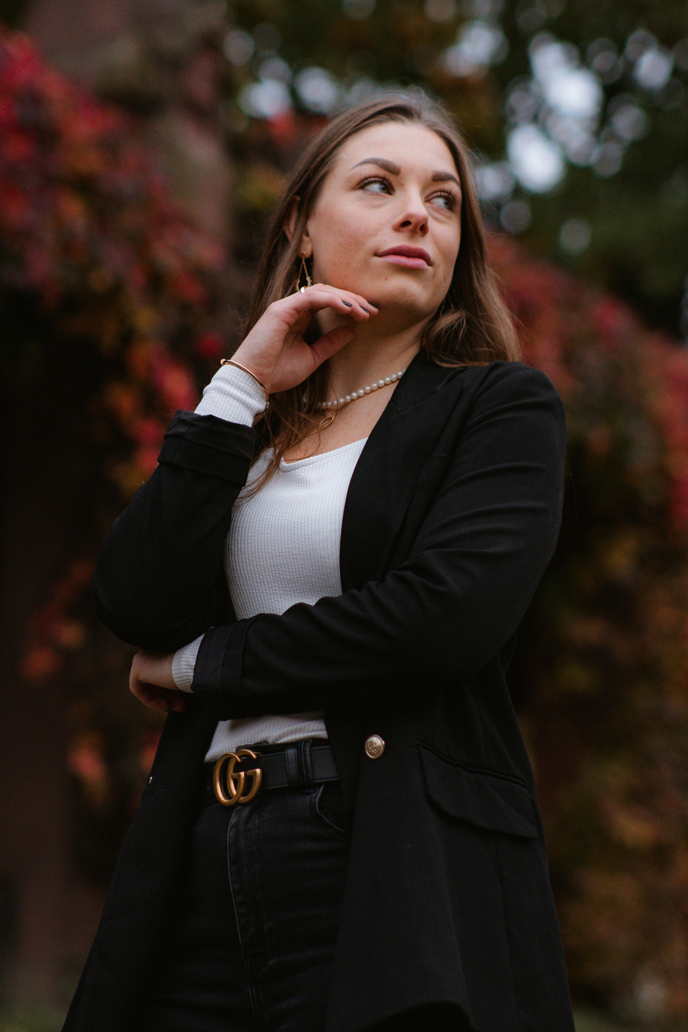 A woman standing in front of a tree with her hand on her chin