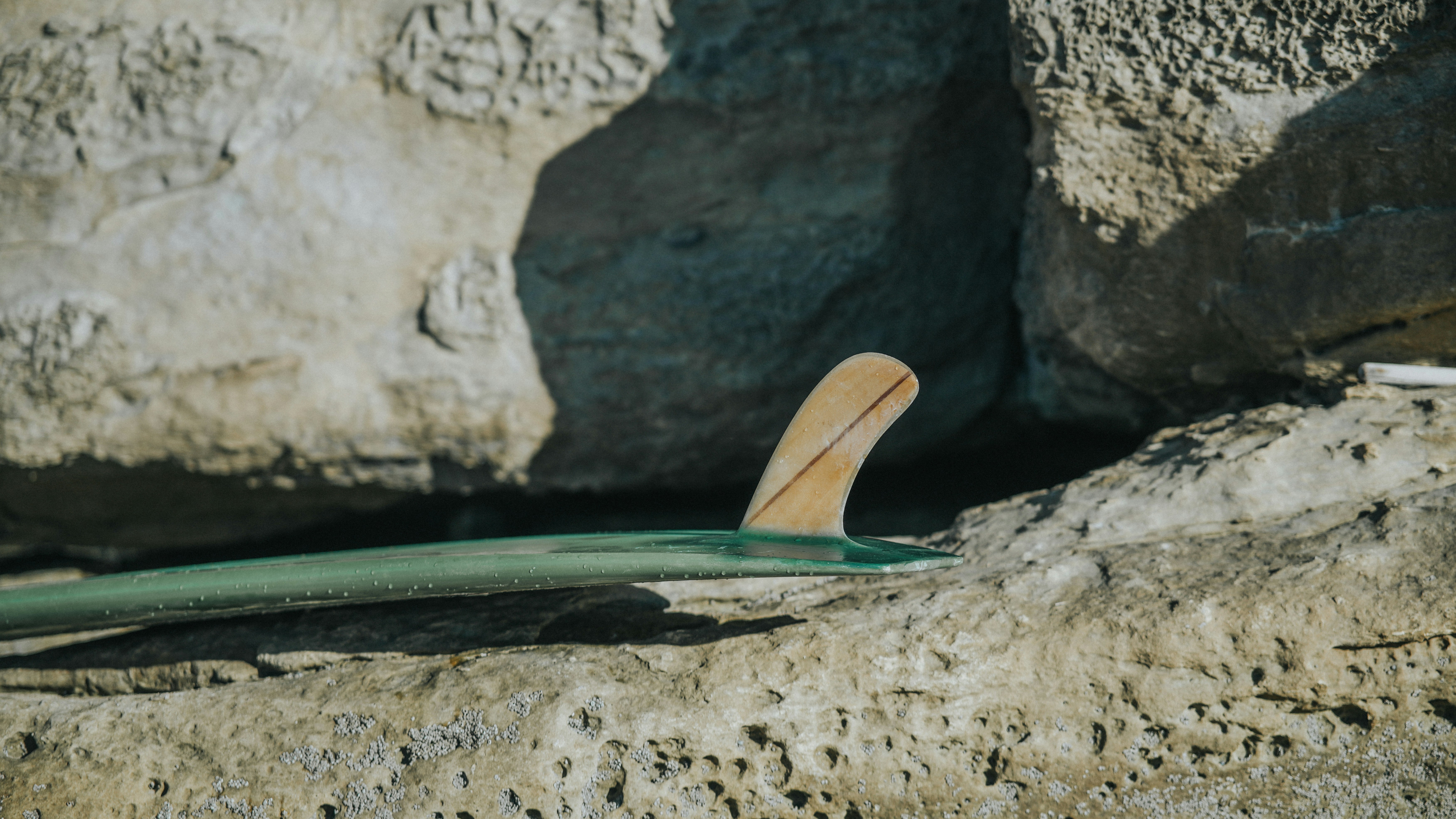 Uma prancha de surf deitada em uma rocha ao lado de um corpo de água