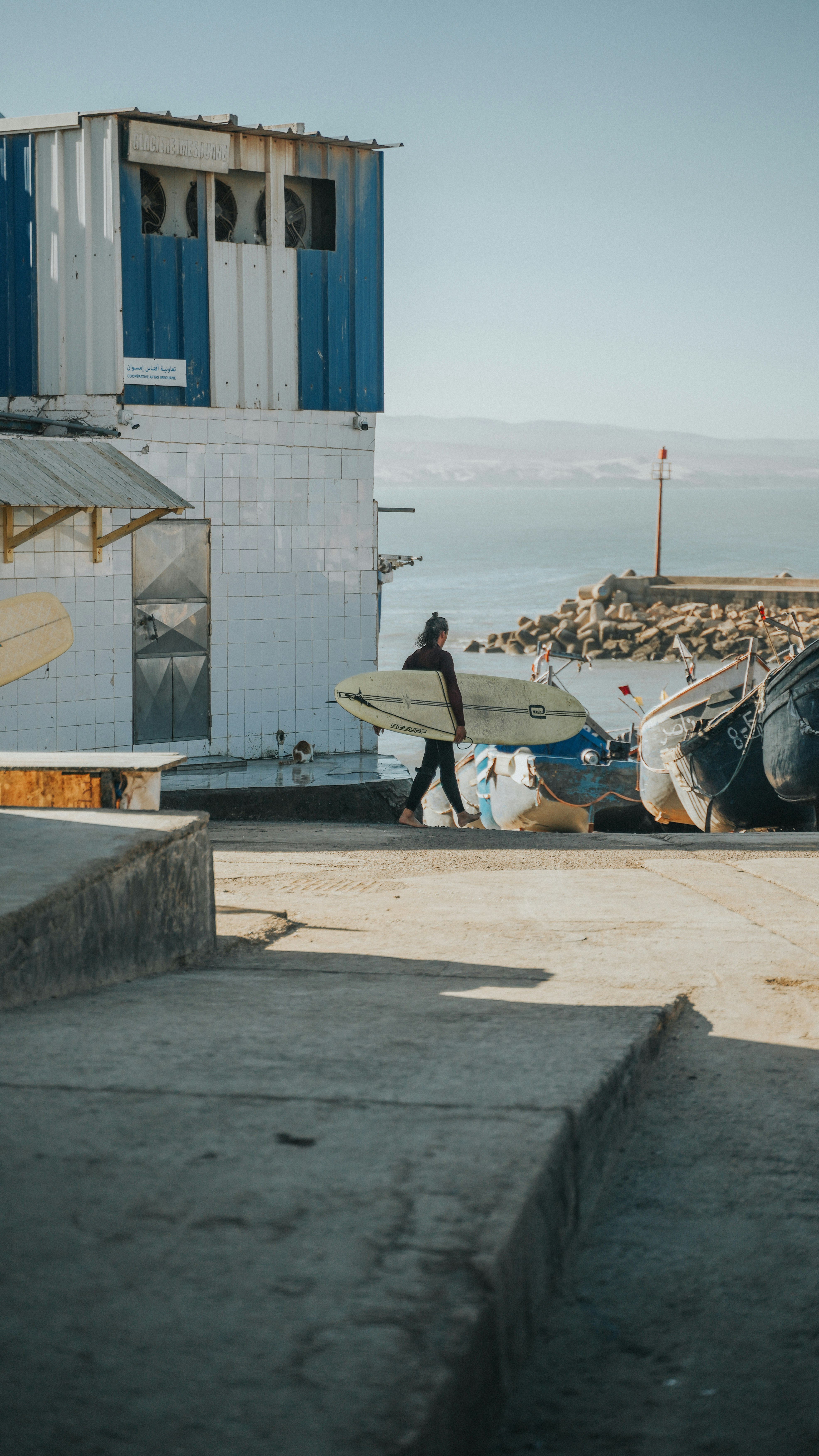Un homme tenant une planche de surf à côté d’un bateau