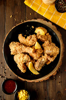 A plate of fried chicken with a side of mustard and ketchup