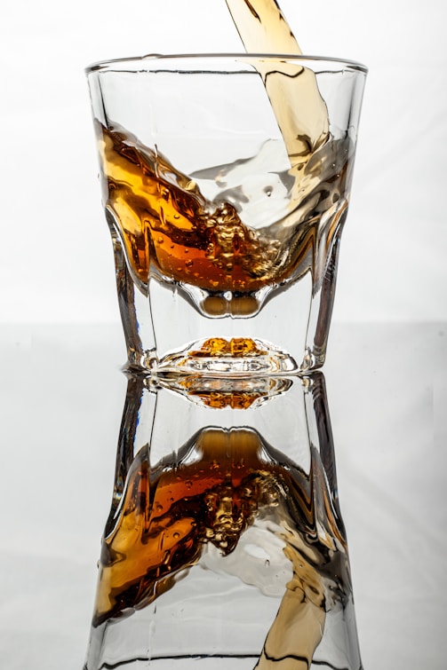 A glass filled with liquid being poured into it