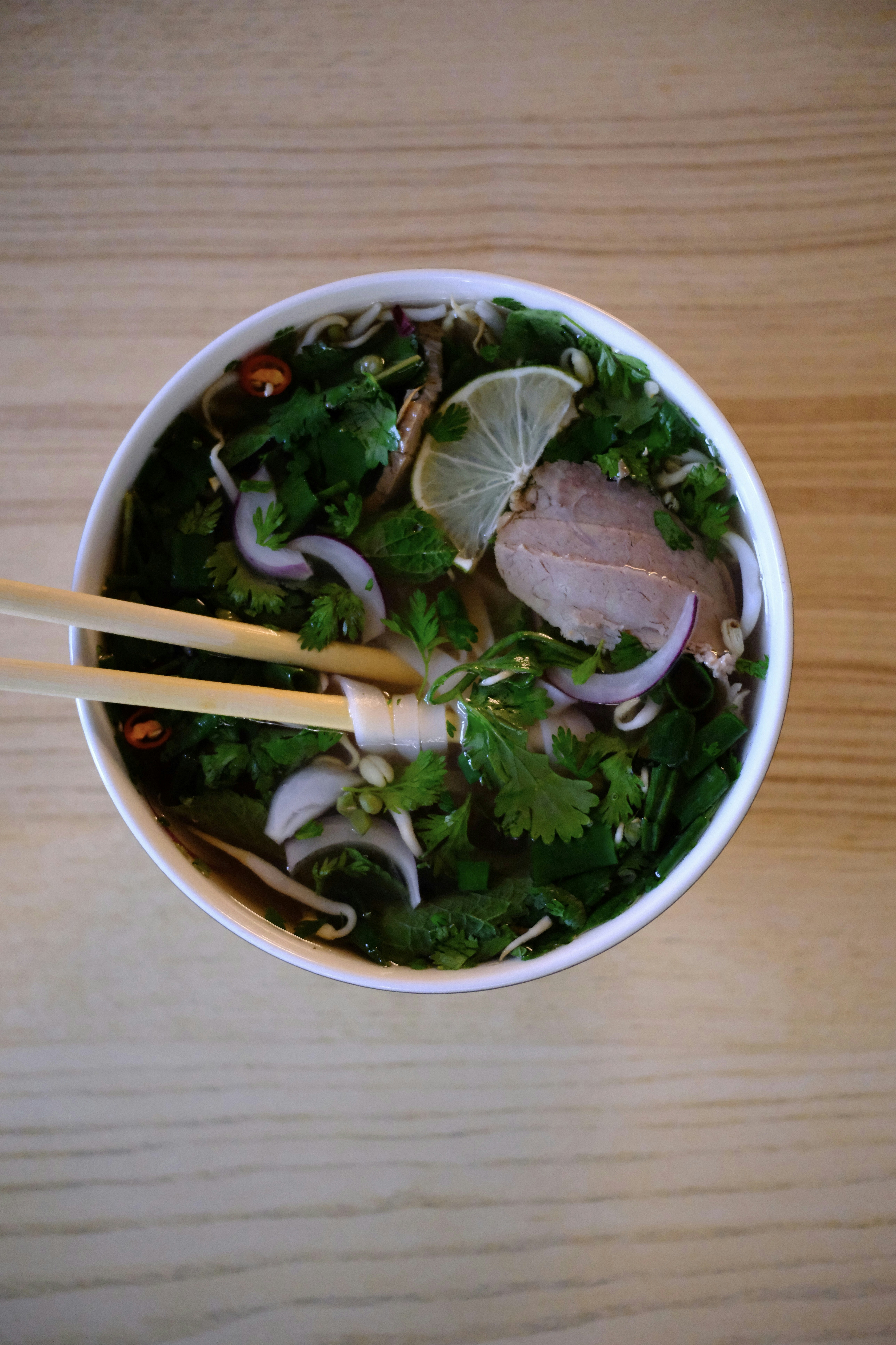 A bowl of food with chopsticks on a table