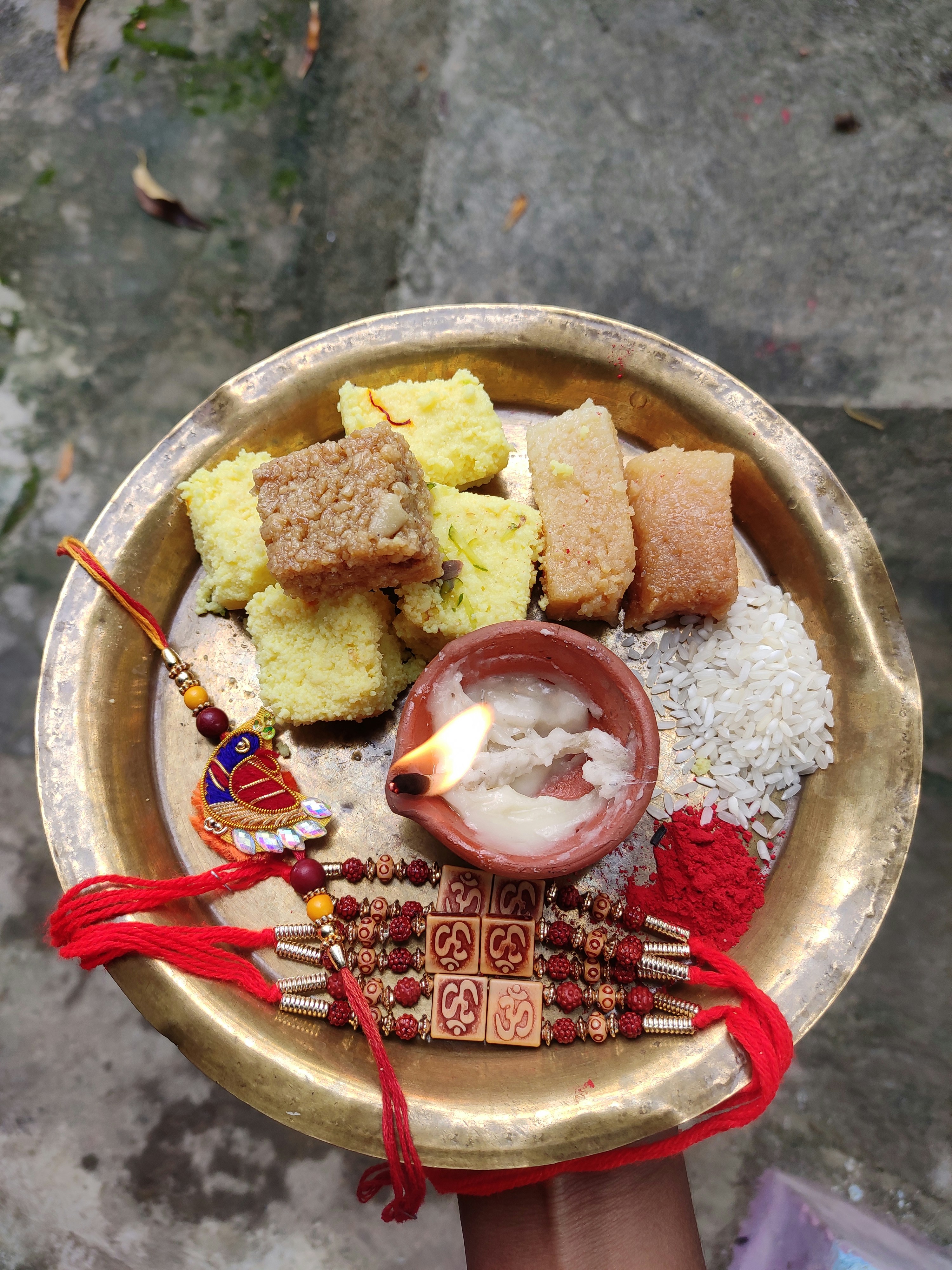 Elegant arrangement of traditional Gujarati sweets on brass plate with diyas
