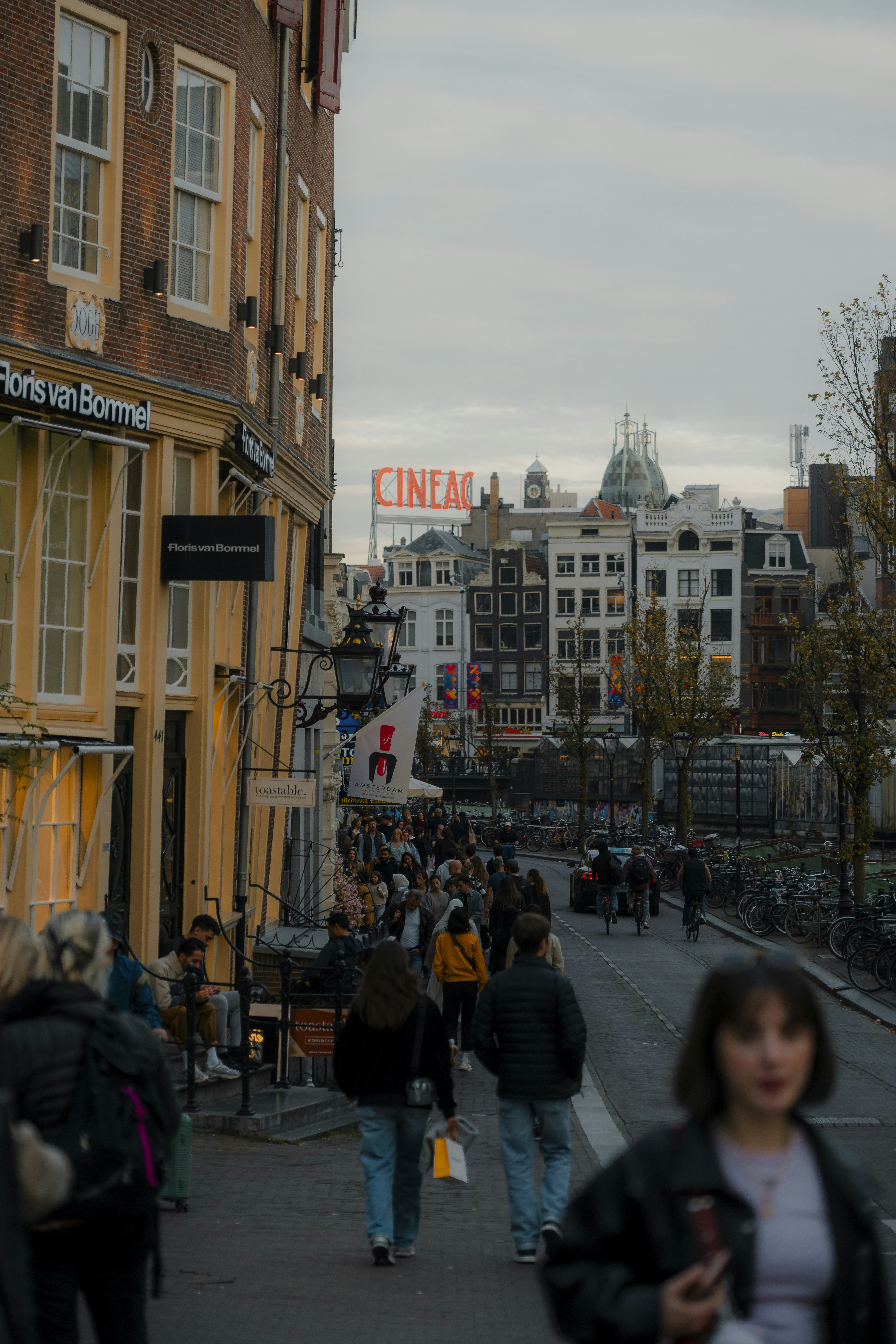 A group of people walking down a street next to tall buildings
