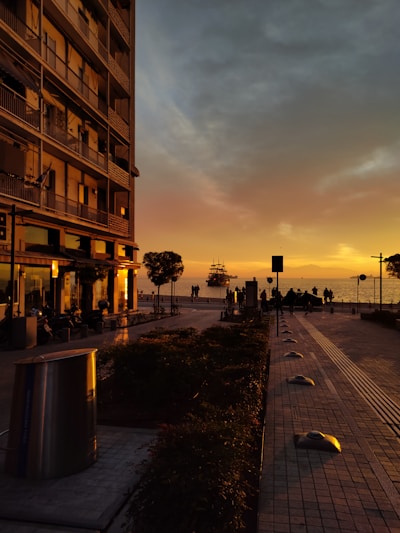A city street at sunset with people walking on the sidewalk