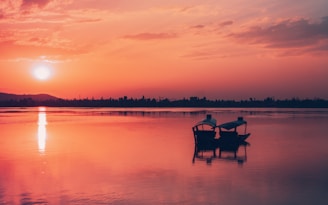 Two people sitting on a bench in the middle of a lake