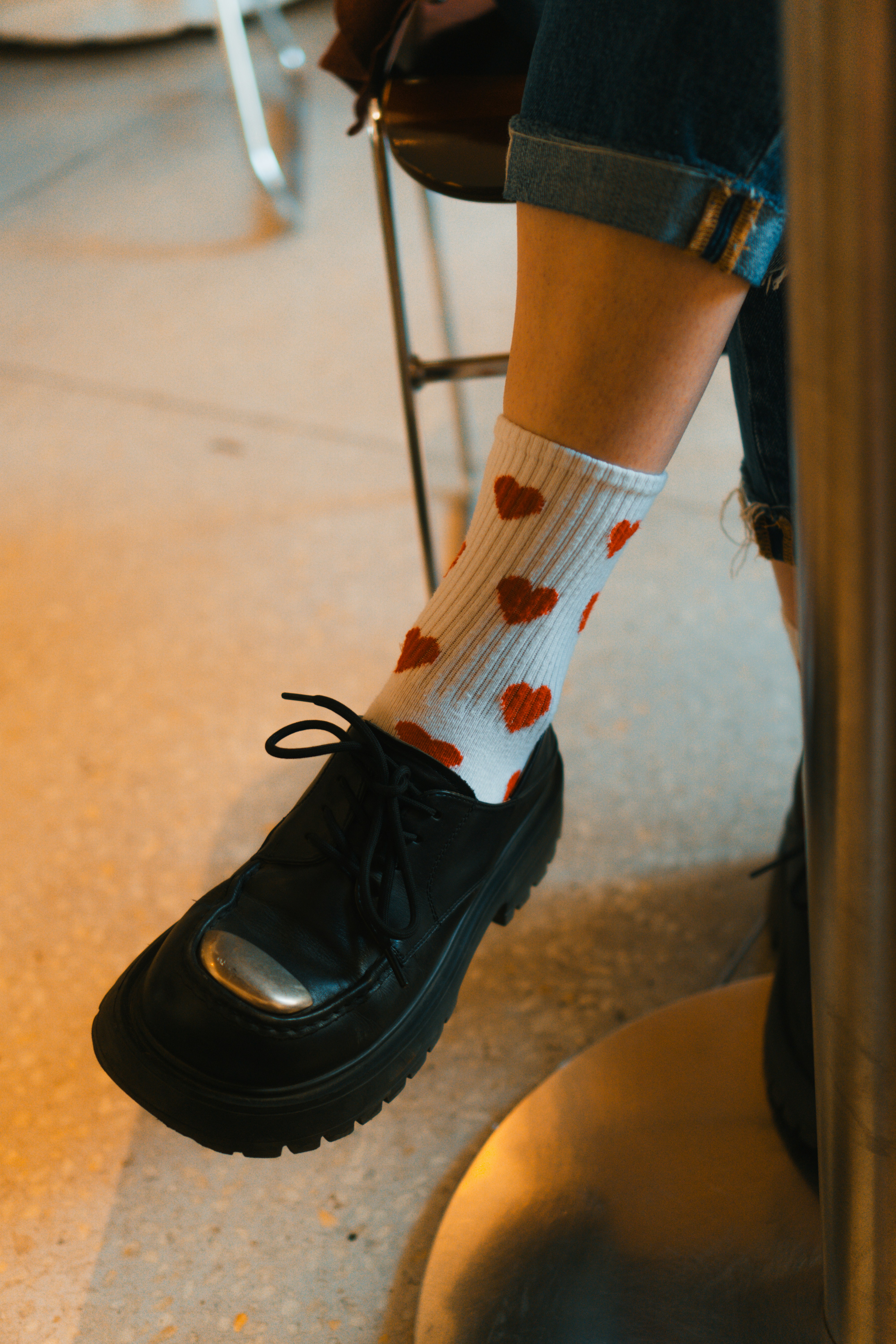 A person sitting on a stool wearing a pair of black shoes
