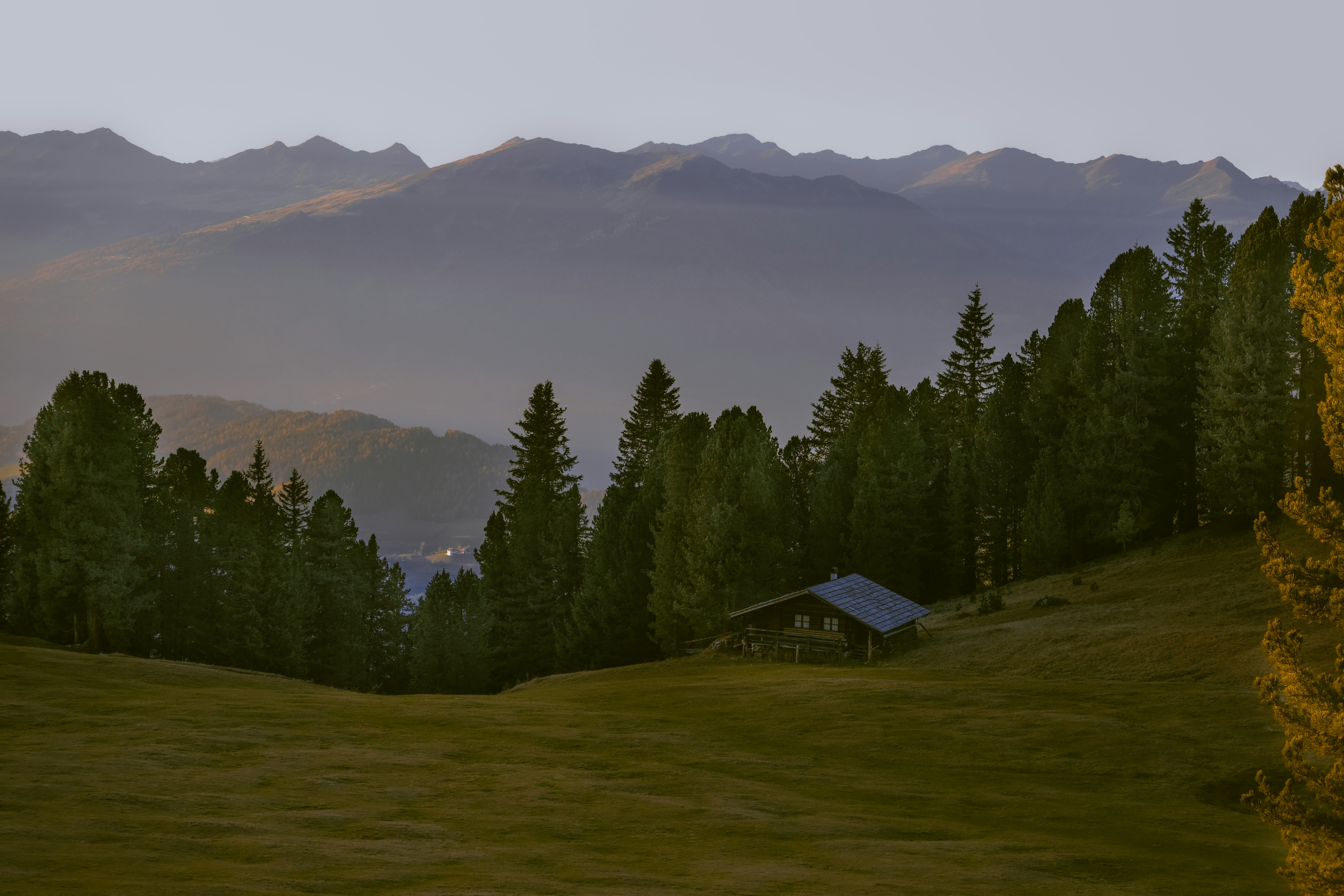 A painting of a mountain scene with a house in the foreground