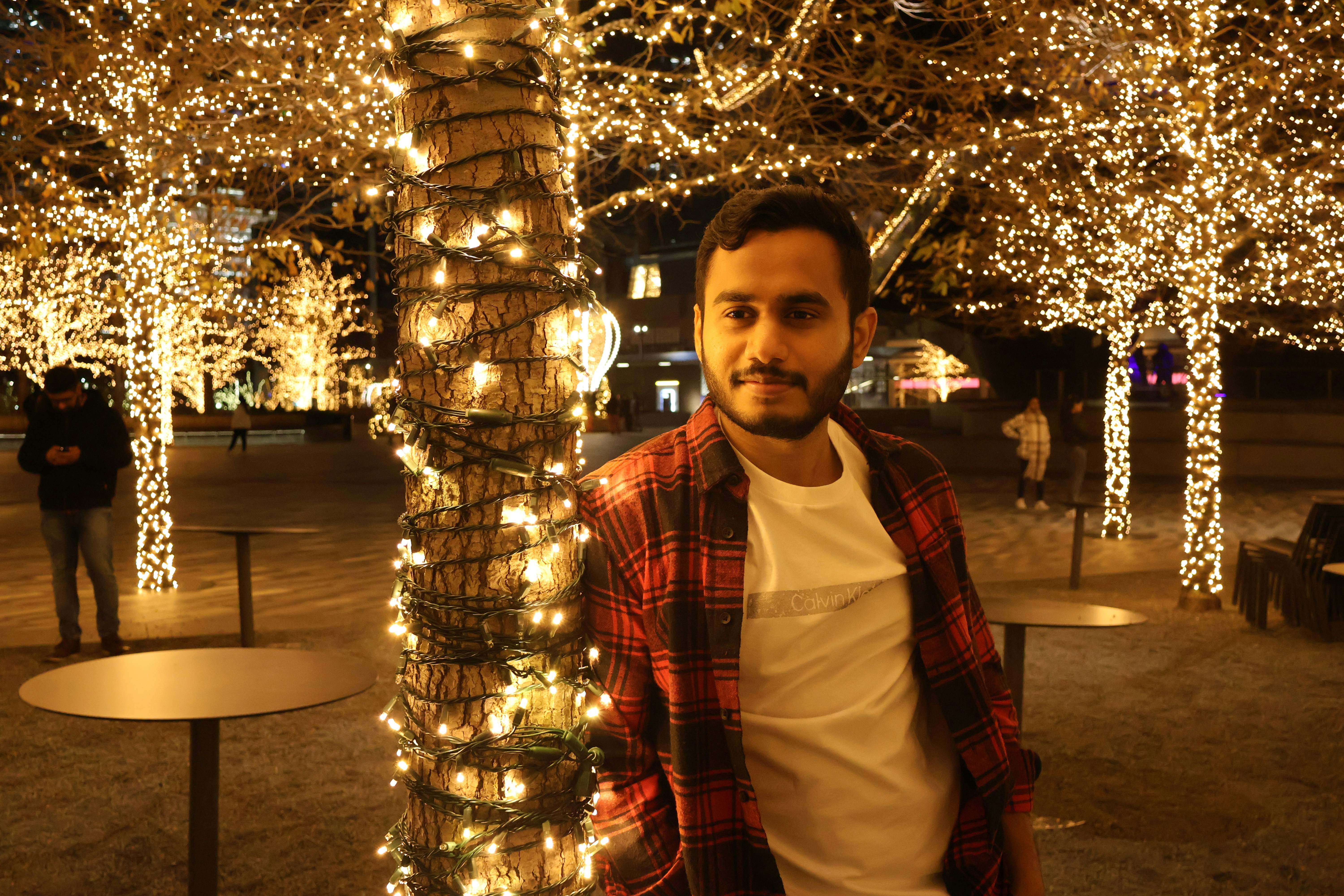 A man standing next to a pole covered in lights