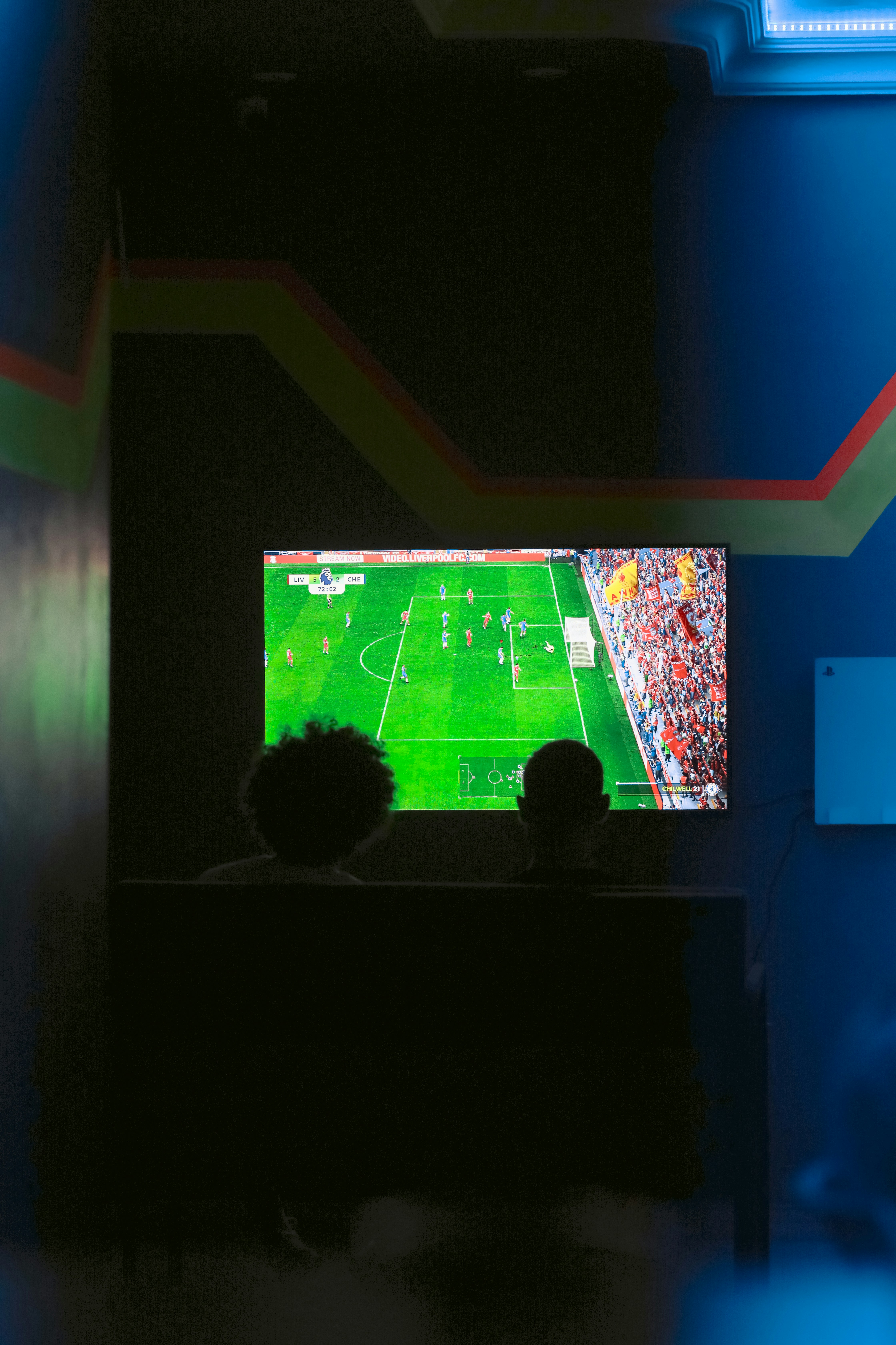 Two people watching a soccer game on a television