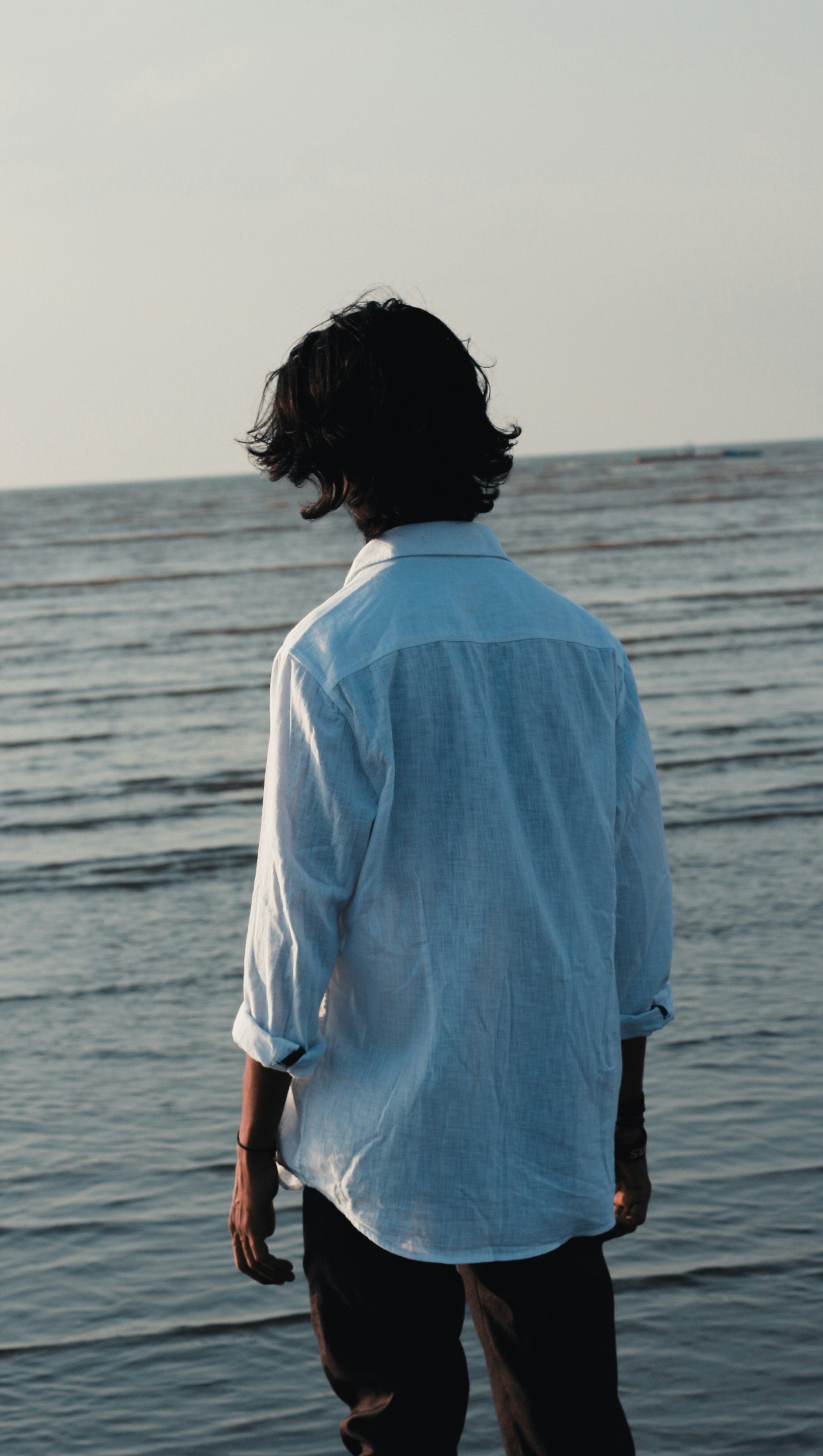 A man standing on a beach next to the ocean