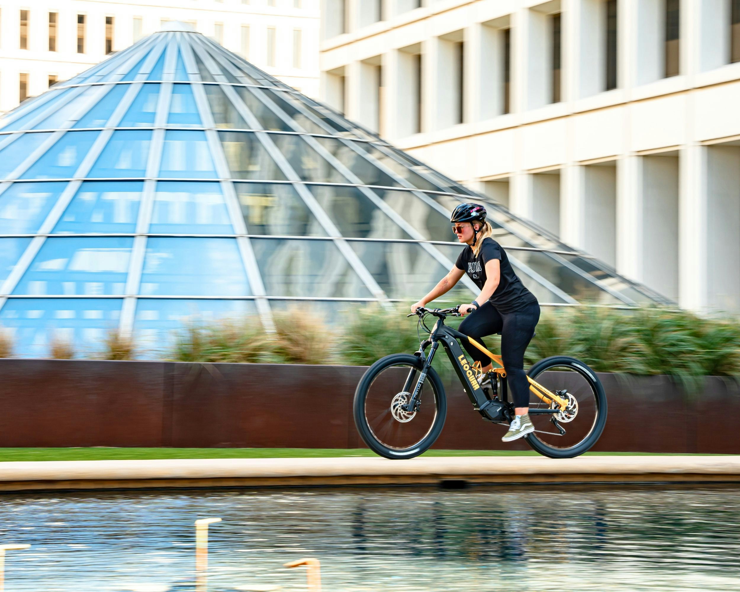 A man riding a bike past a tall building