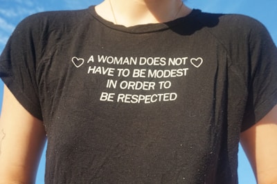 A woman wearing a t - shirt that says a woman does not have to be