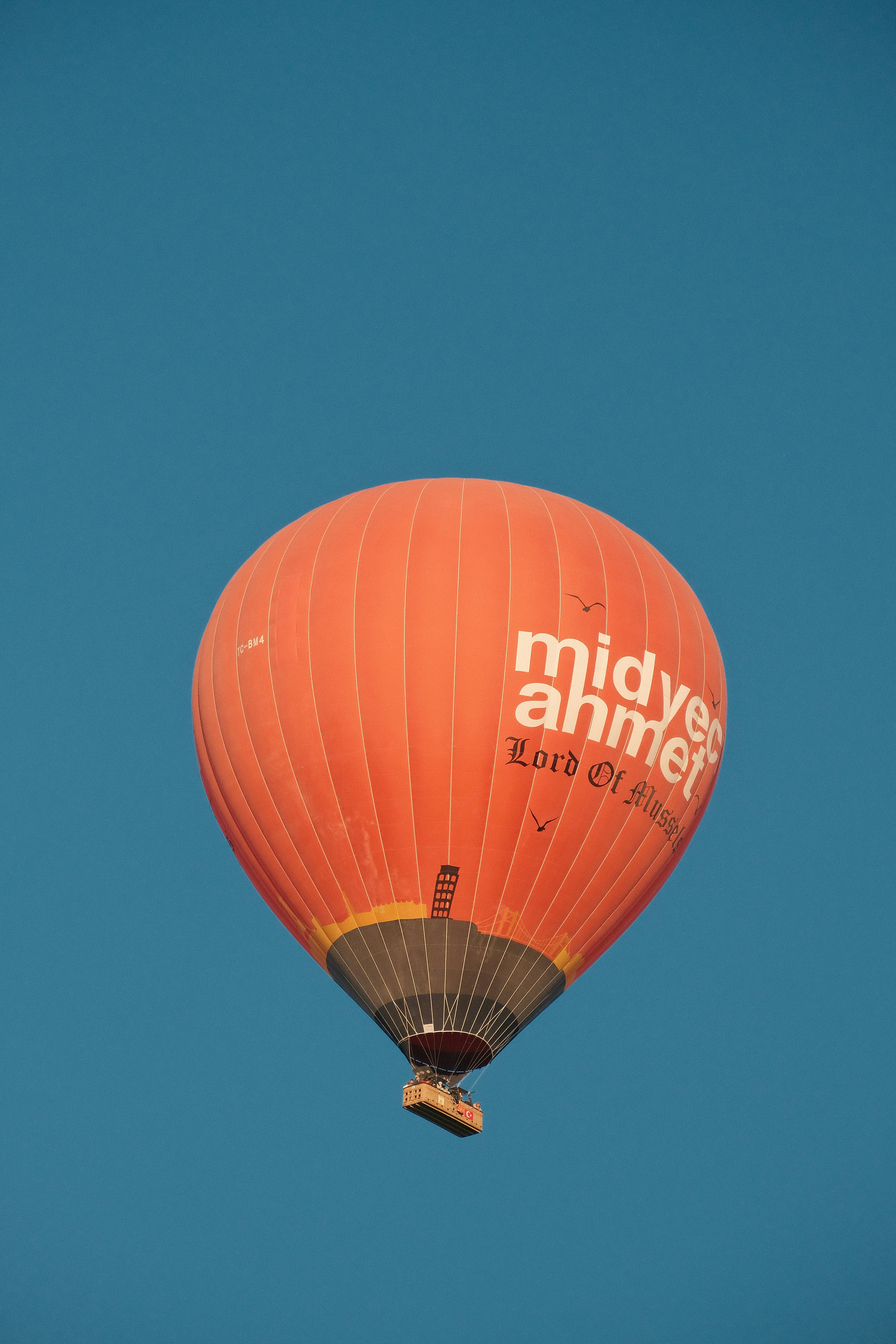 Ein großer orangefarbener Heißluftballon, der durch den blauen Himmel fliegt