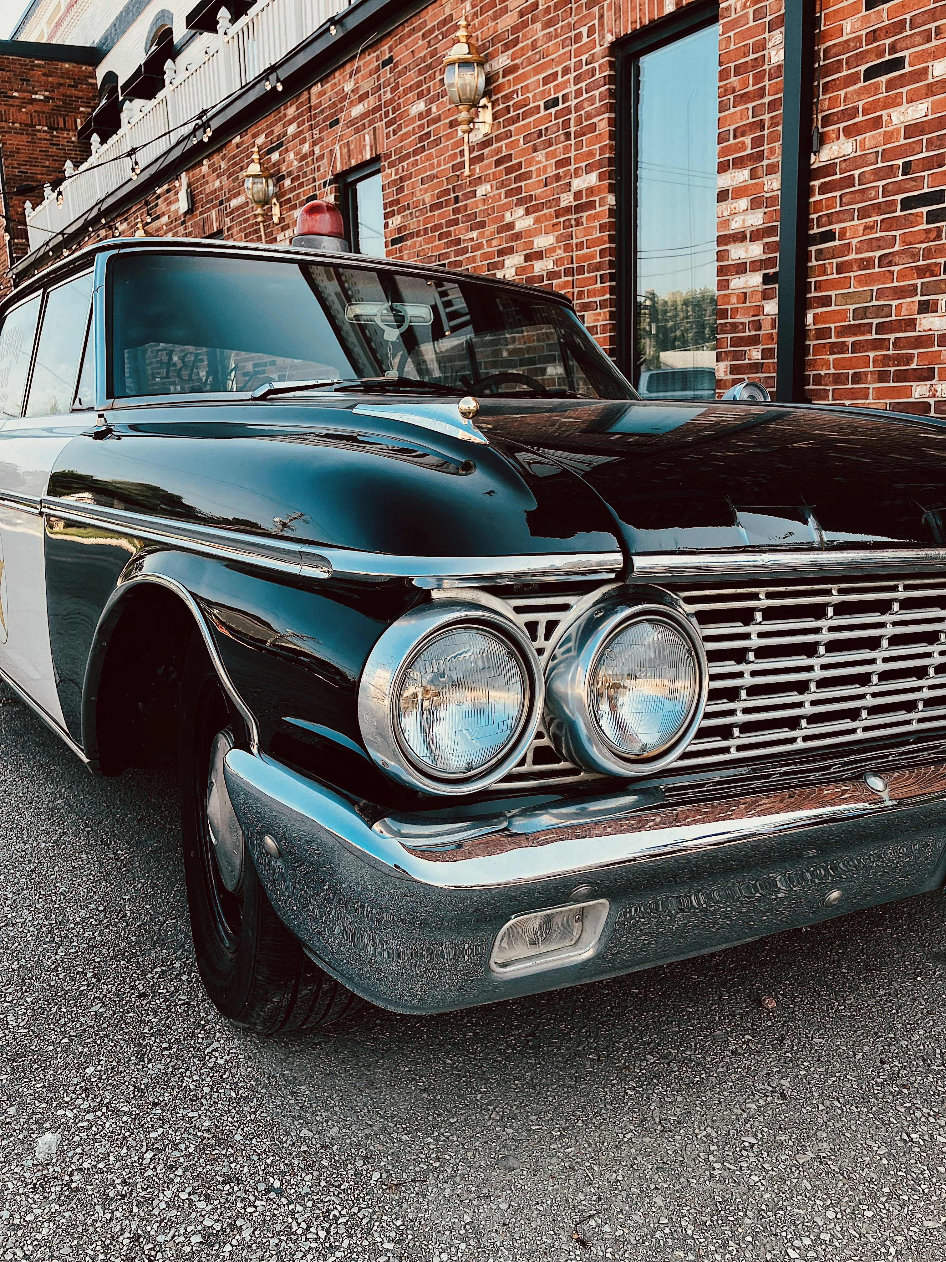 A black and white car parked in front of a brick building