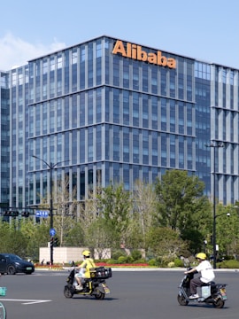 A group of people riding scooters in front of a tall building