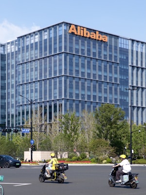 A group of people riding scooters in front of a tall building