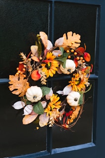 A fall wreath is hanging on a window sill