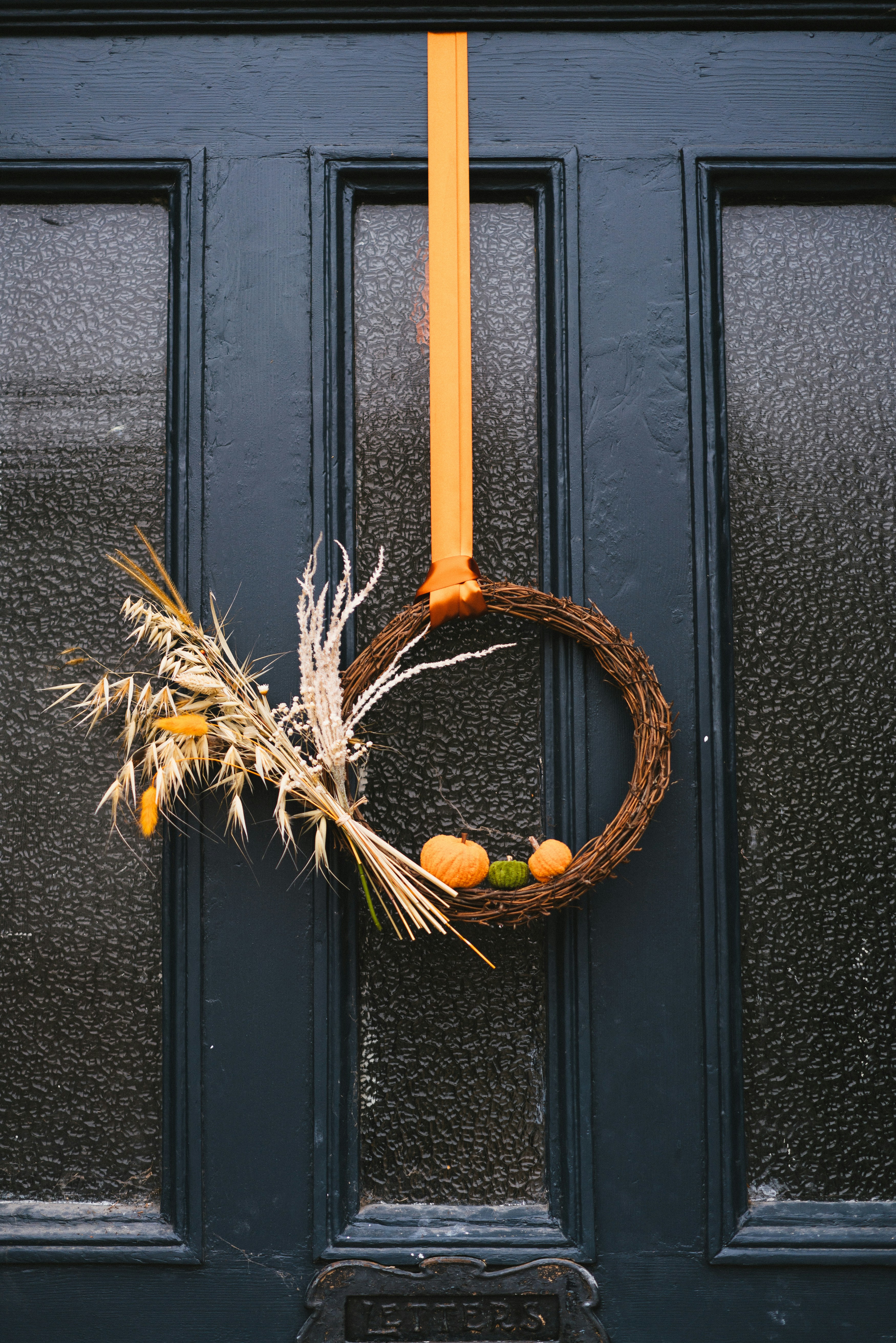 Fall door decor wreath with warm autumn colors hanging on a front door