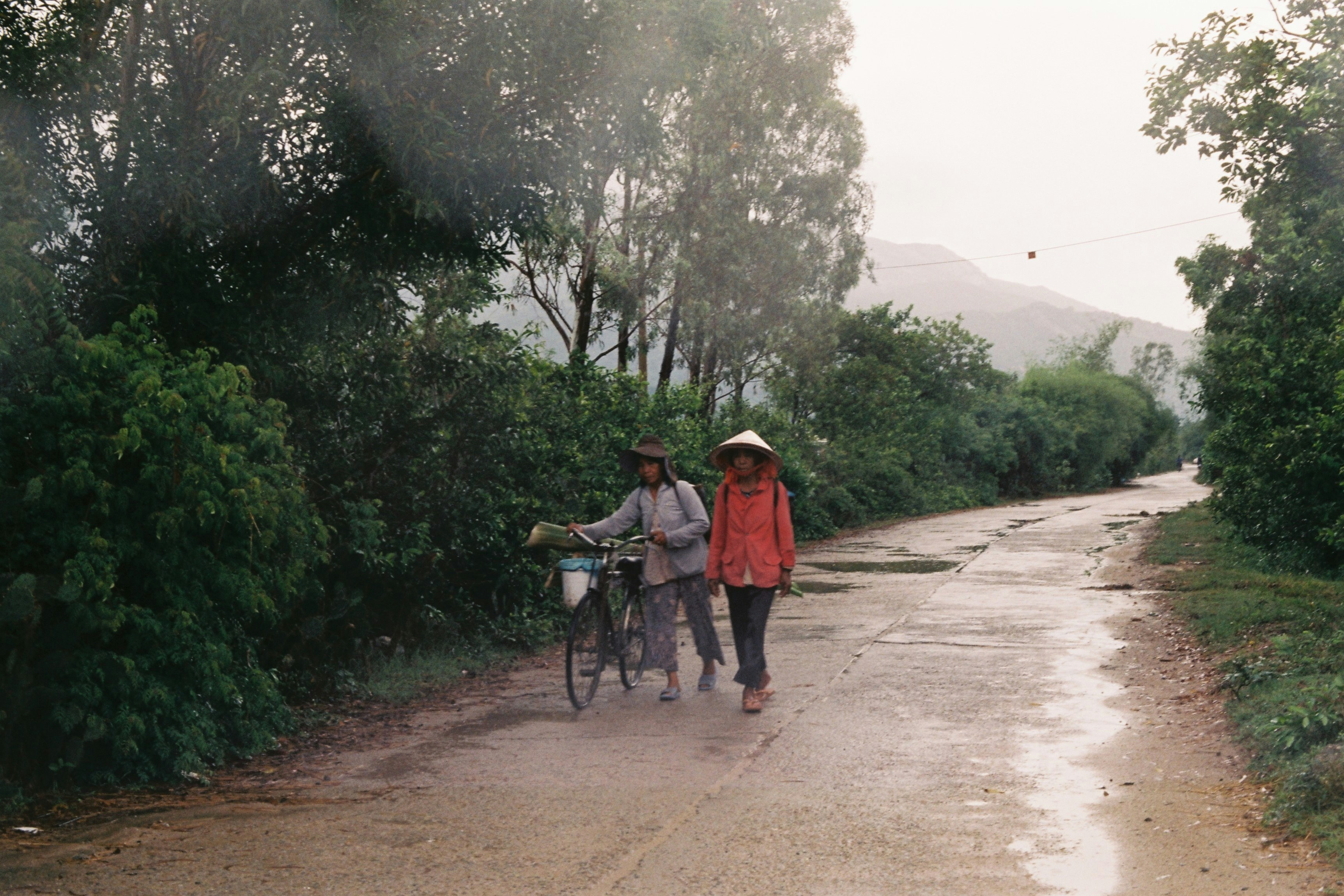 A couple of people walking down a dirt road