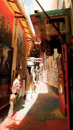 A narrow alley with a lot of paintings on the walls
