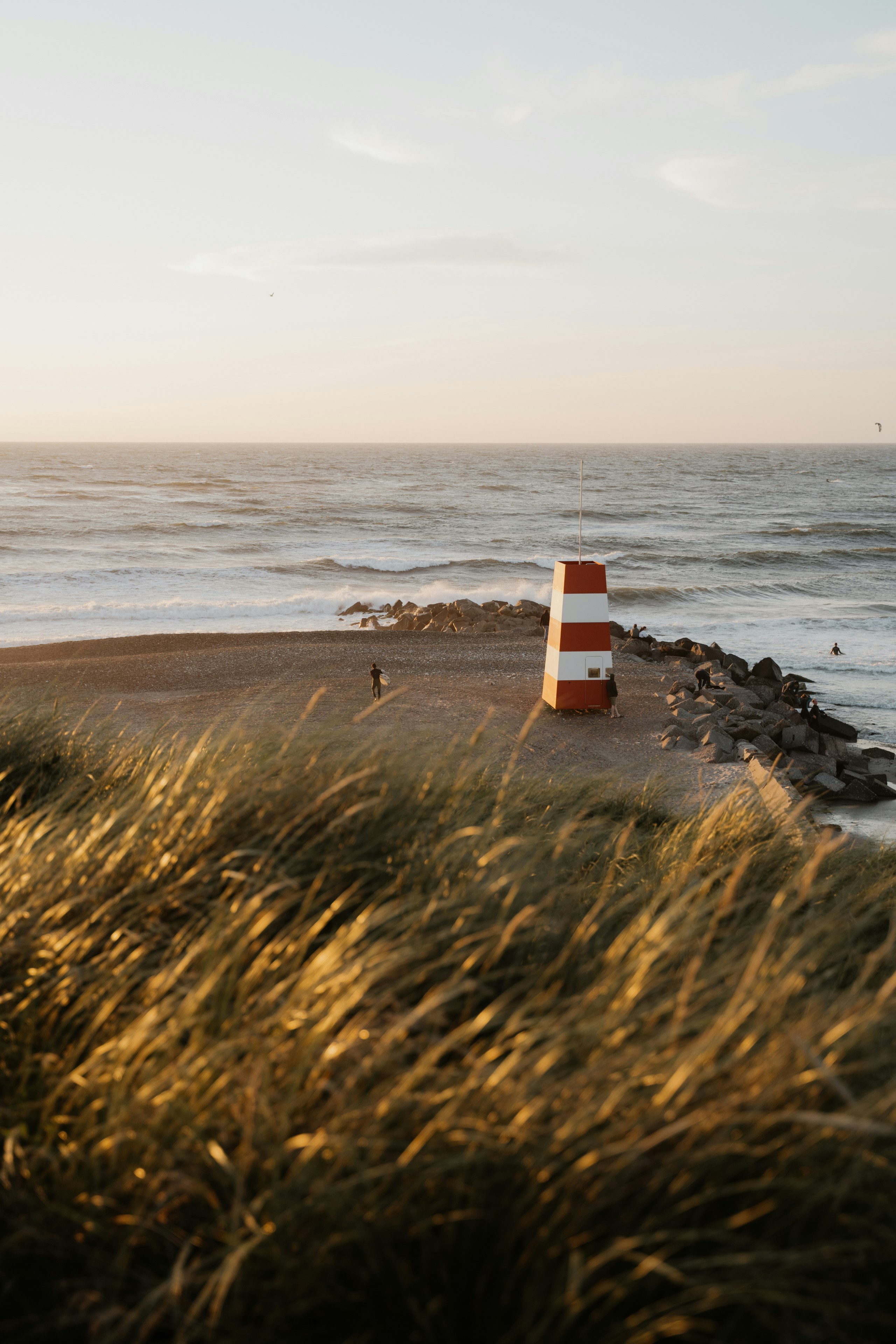 A red and white buoy sitting on top of a beach next to the ocean