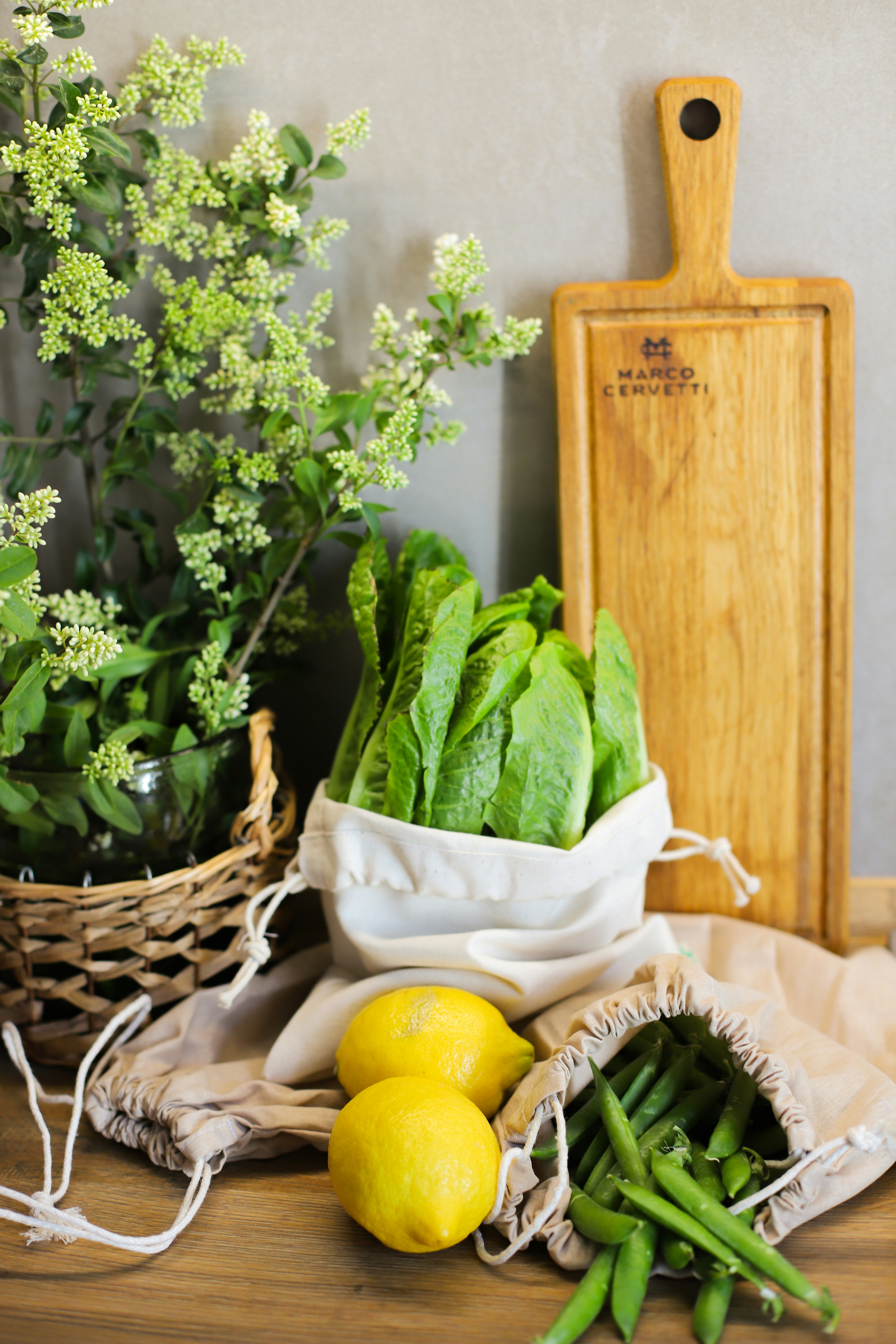 A table topped with lemons and vegetables next to a cutting board
