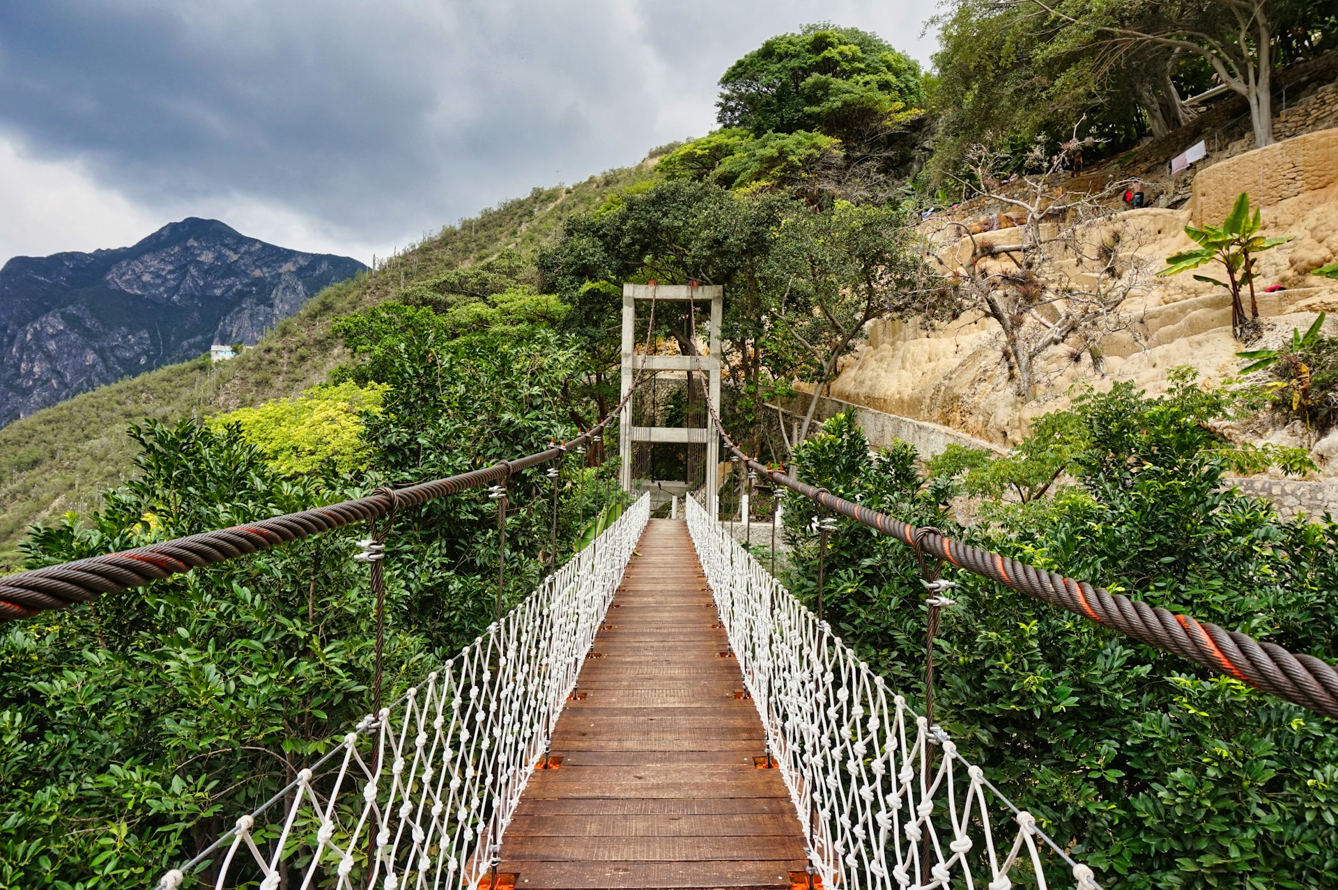 A wooden suspension bridge over a lush green hillside