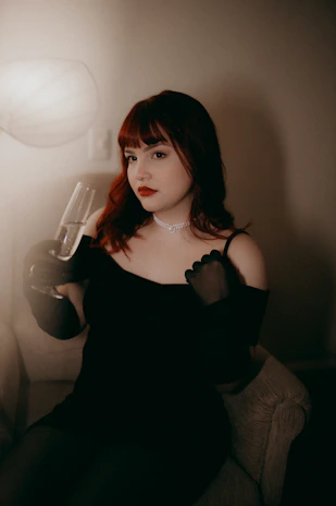 A woman in a black dress sitting on a couch