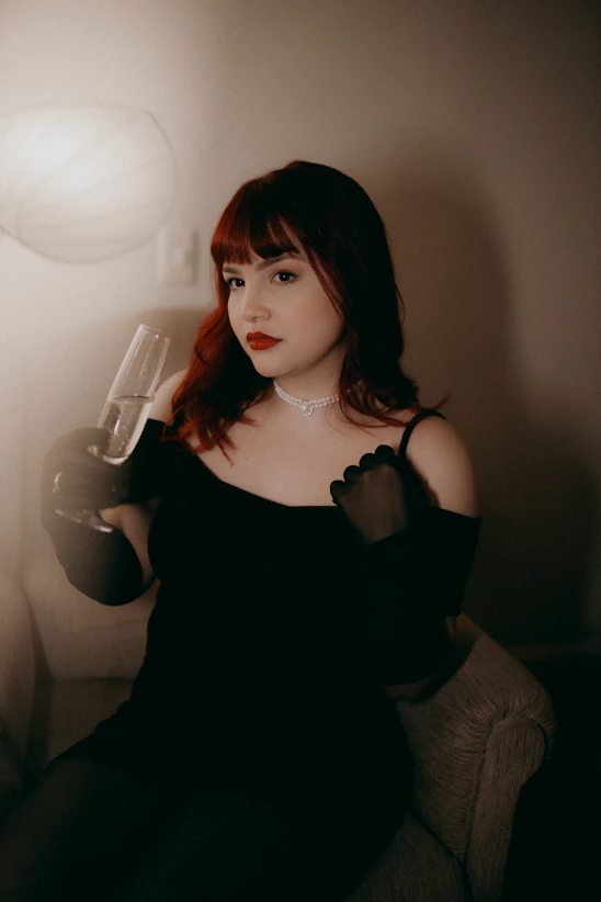 A woman in a black dress sitting on a couch