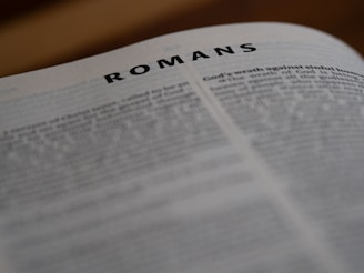 A close up of an open book with the word romans on it