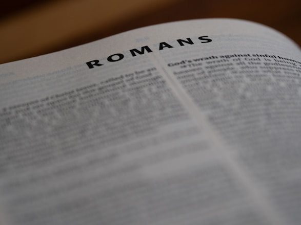 A close up of an open book with the word romans on it