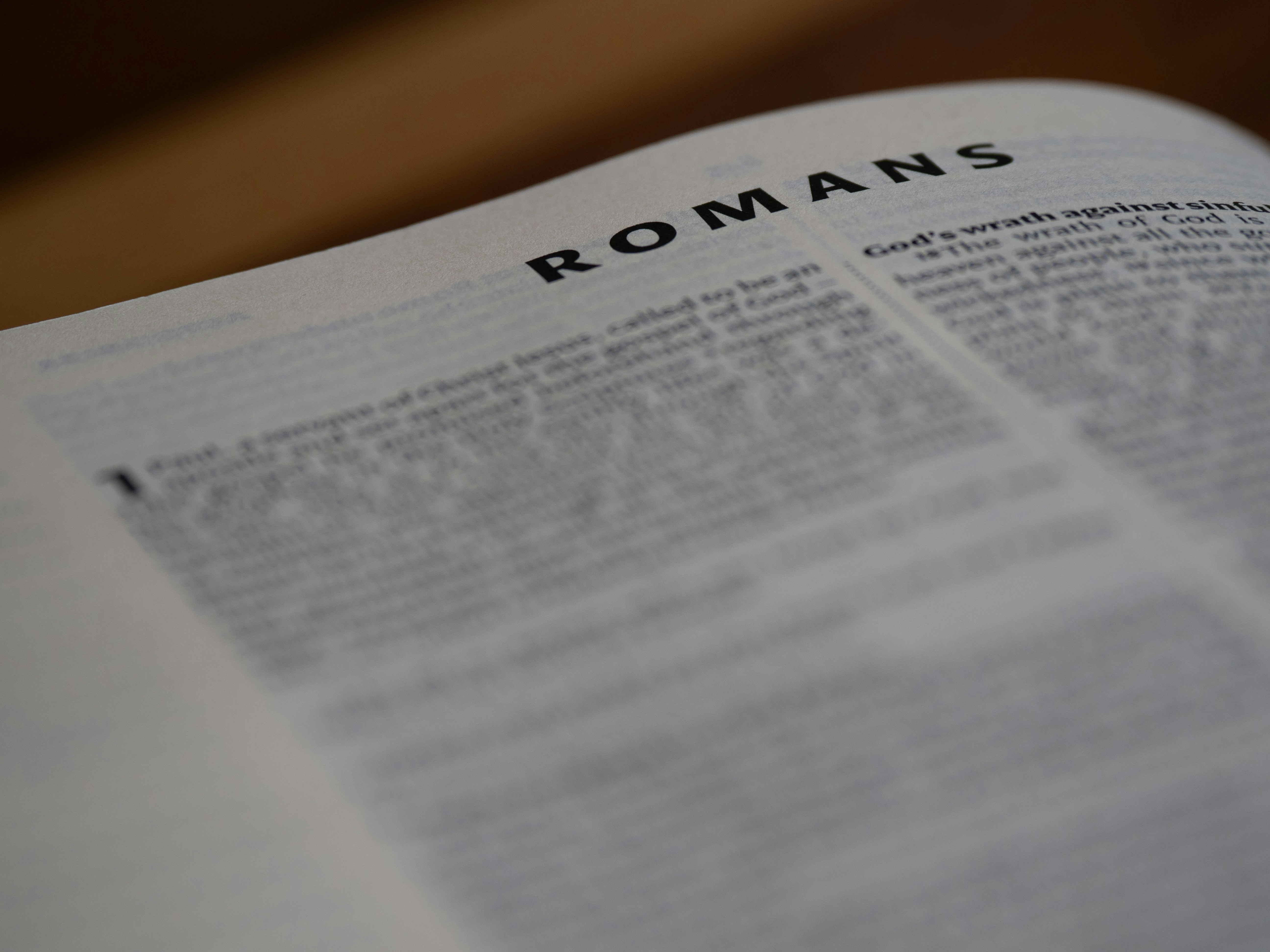 A close up of an open bible with the word romans on it
