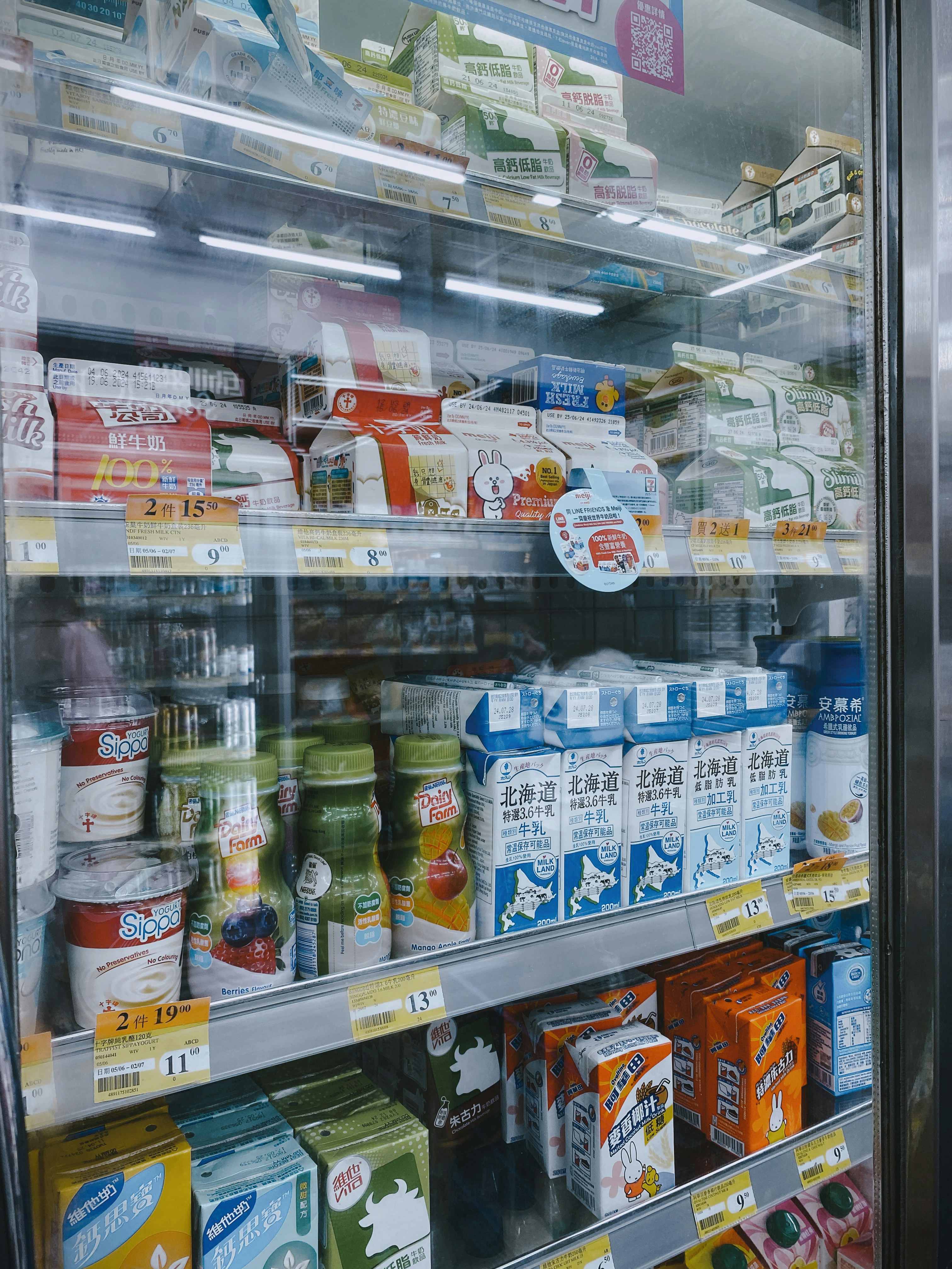 Bottles of fresh milk and dairy products in clean bright refrigerated setting with white background and natural daylight