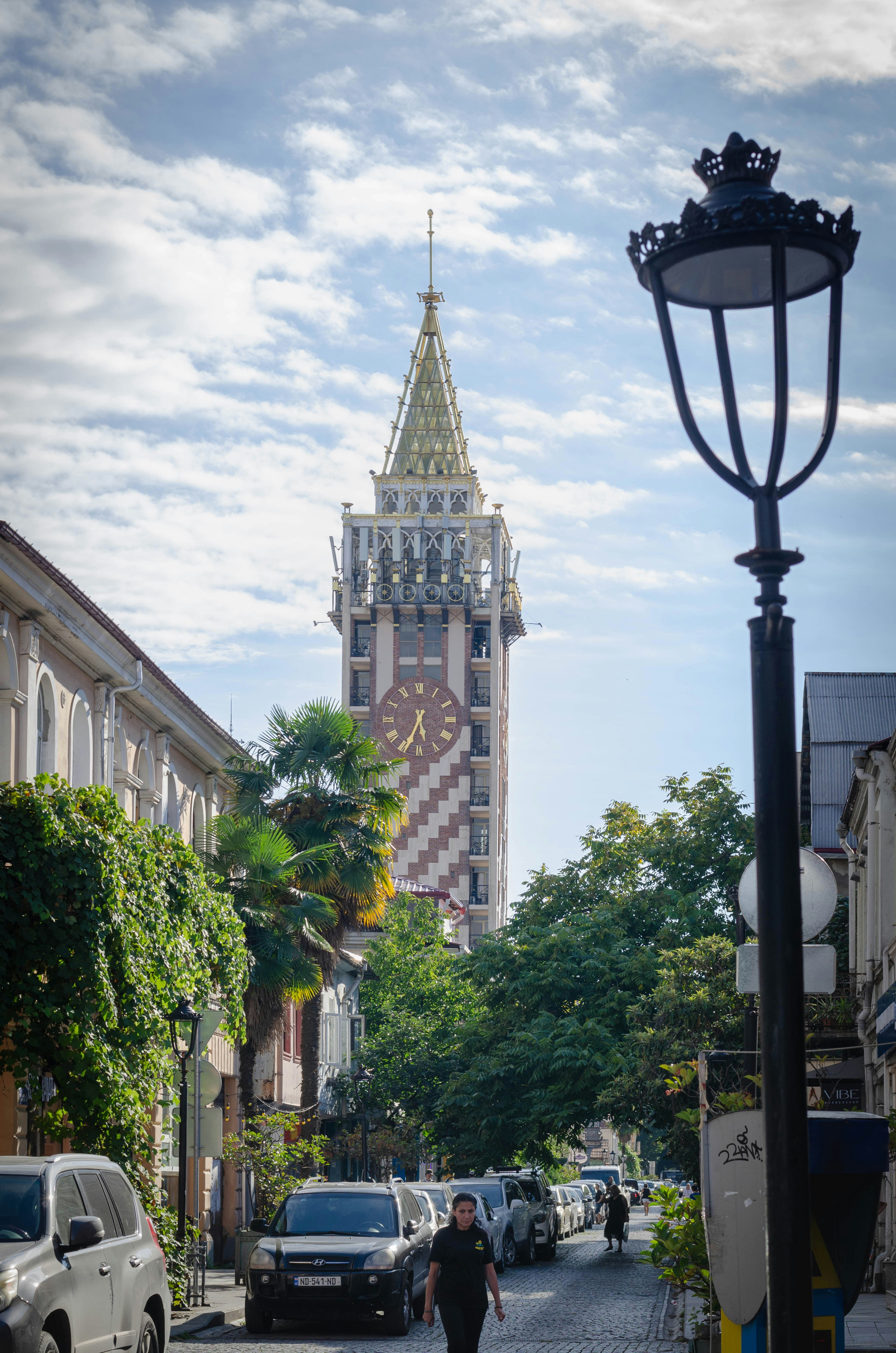A man walking down a street next to a tall clock tower