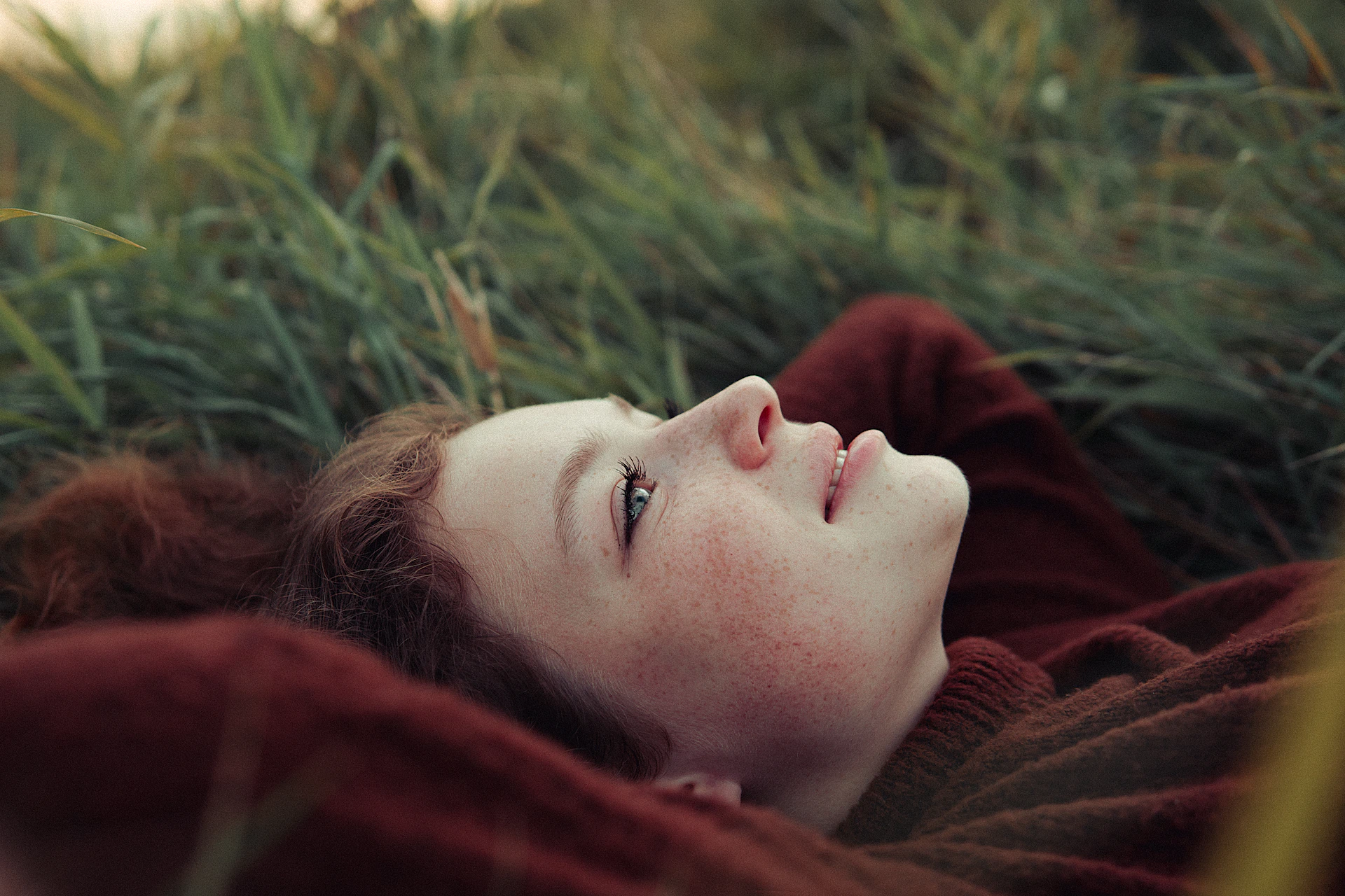 A woman laying in the grass with her eyes closed