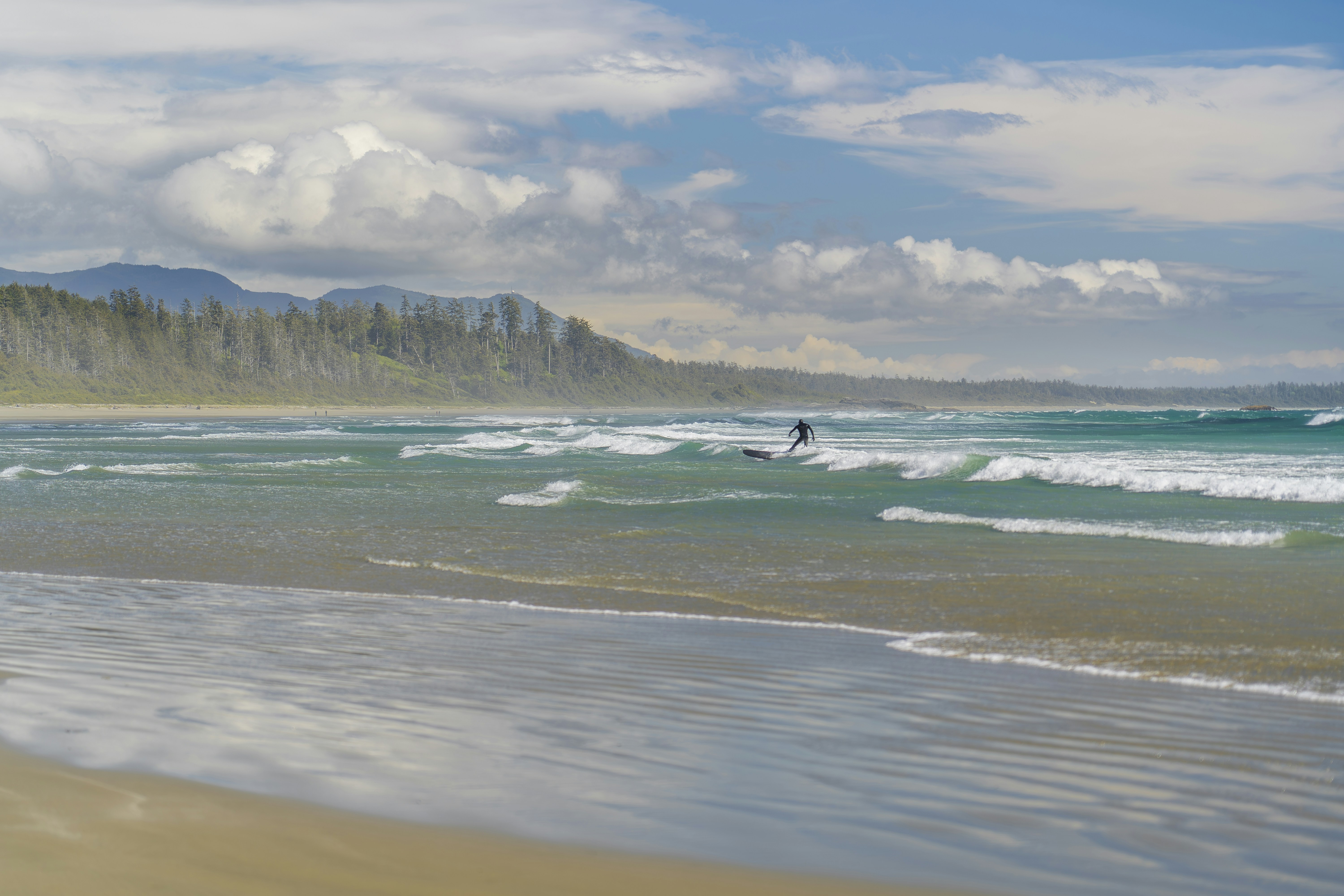 A person riding a surfboard on top of a sandy beach