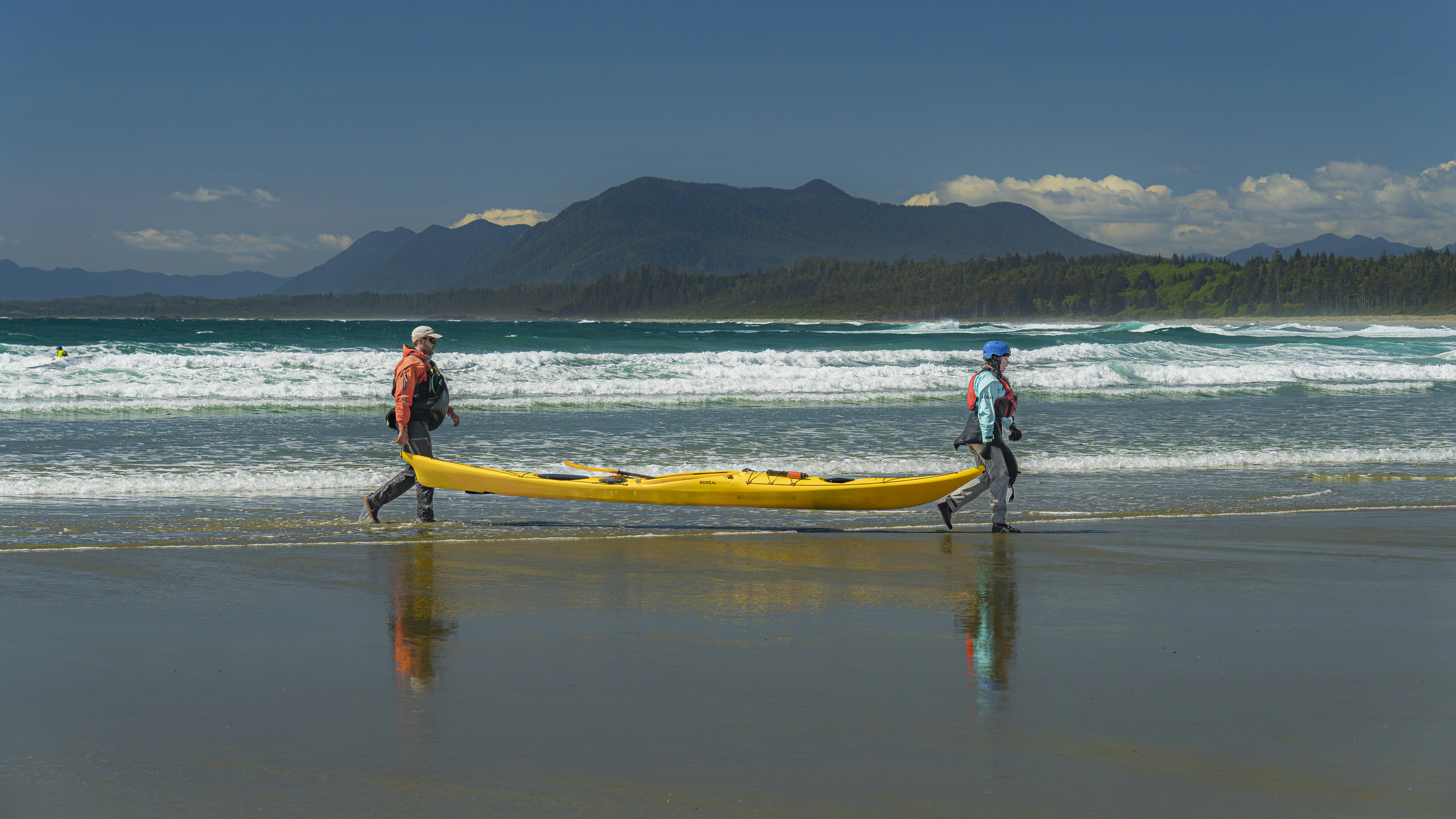 Two people walking on the beach with a surfboard