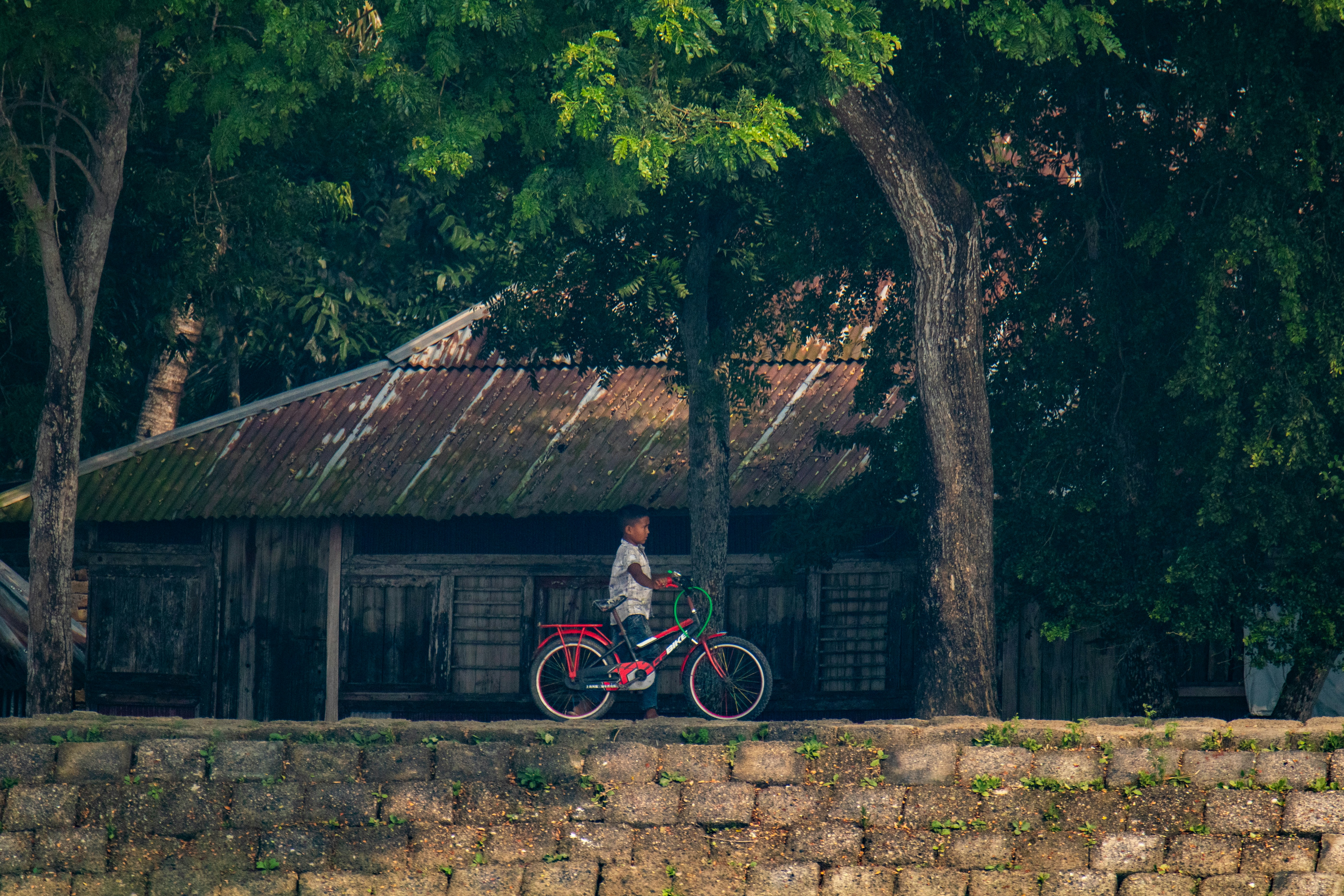 A man riding a bike down a street next to a stone wall