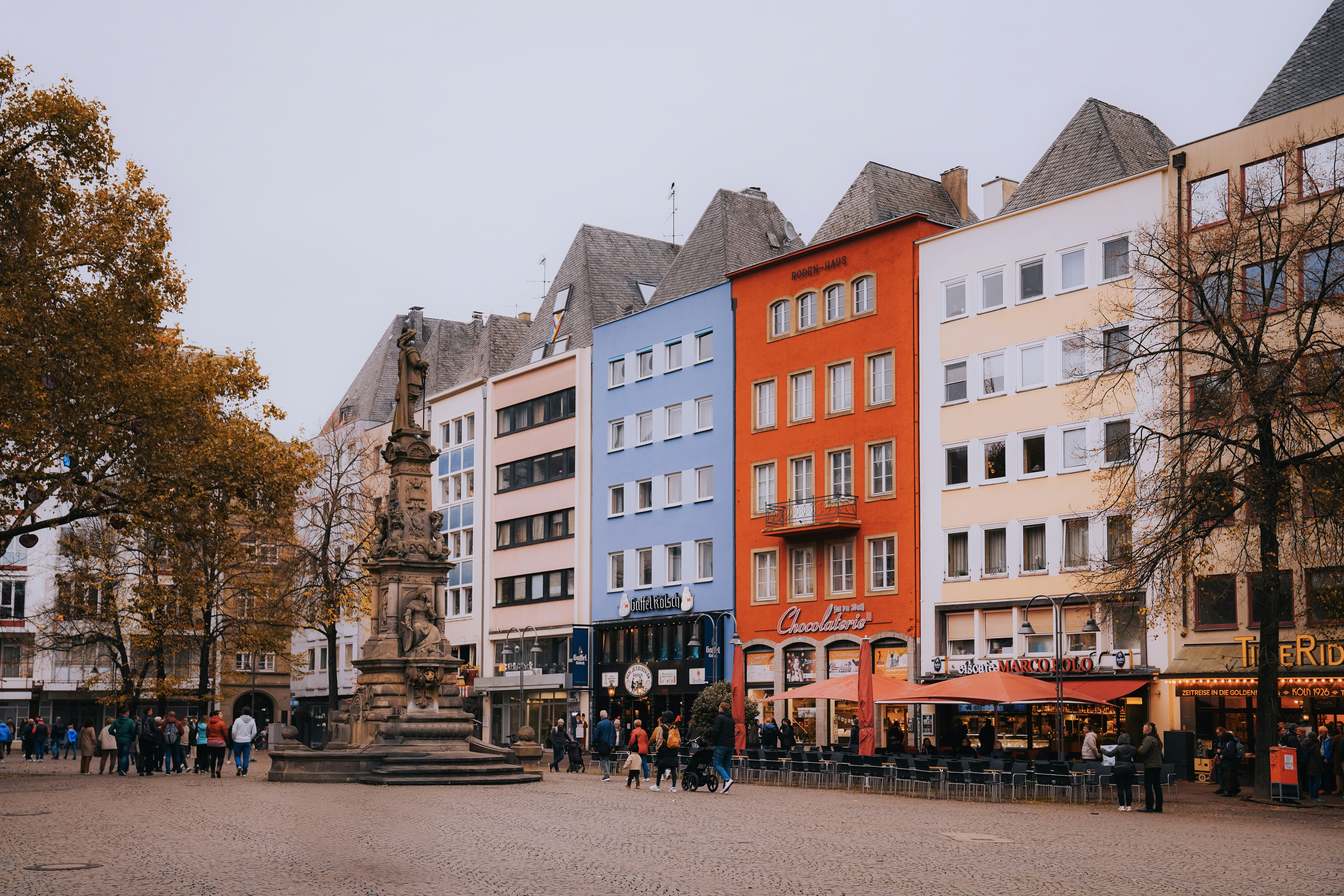 A group of people walking down a street next to tall buildings