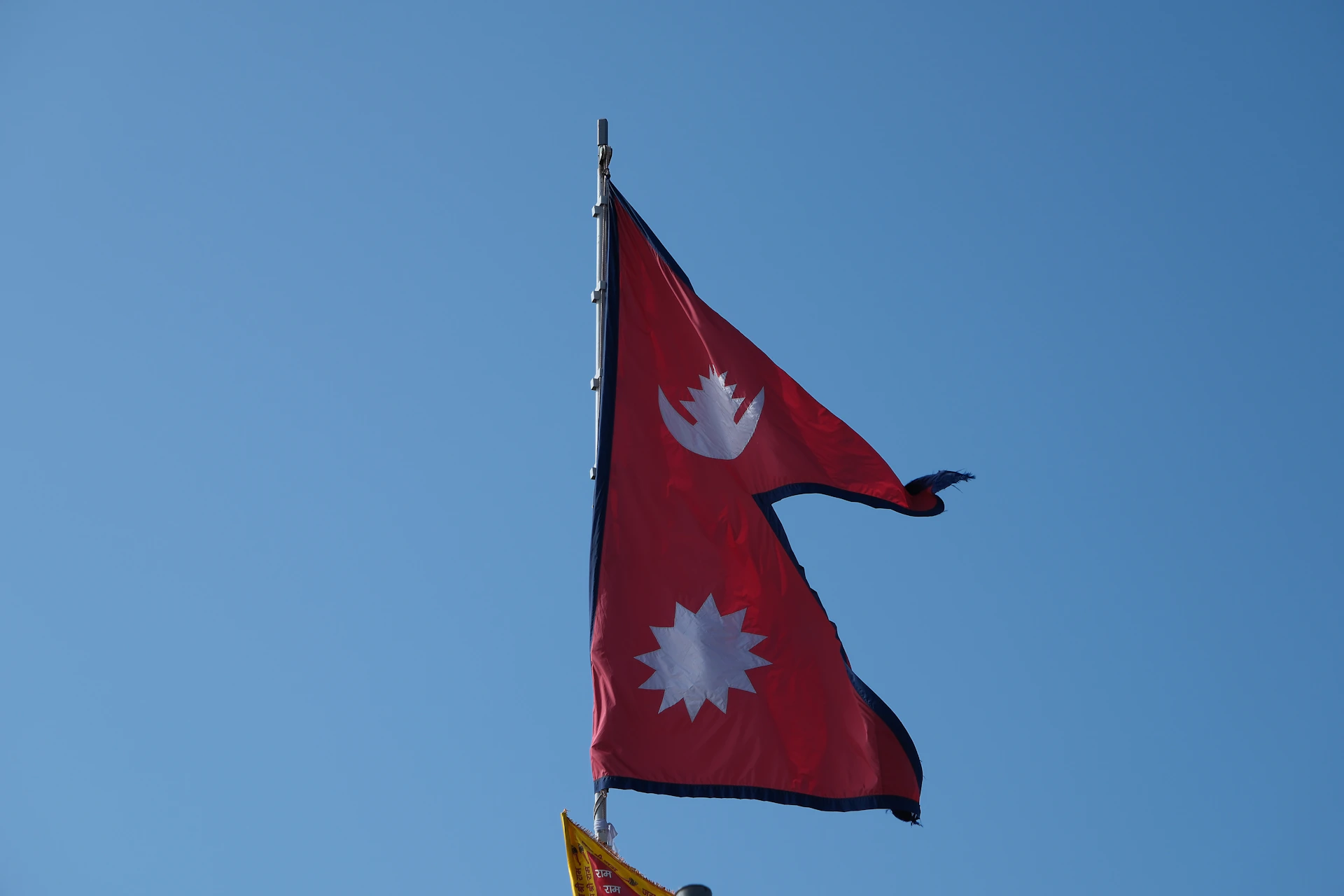 Two flags flying in the wind on a clear day