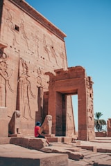 A person sitting in front of an ancient building