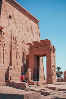 A person sitting in front of an ancient building