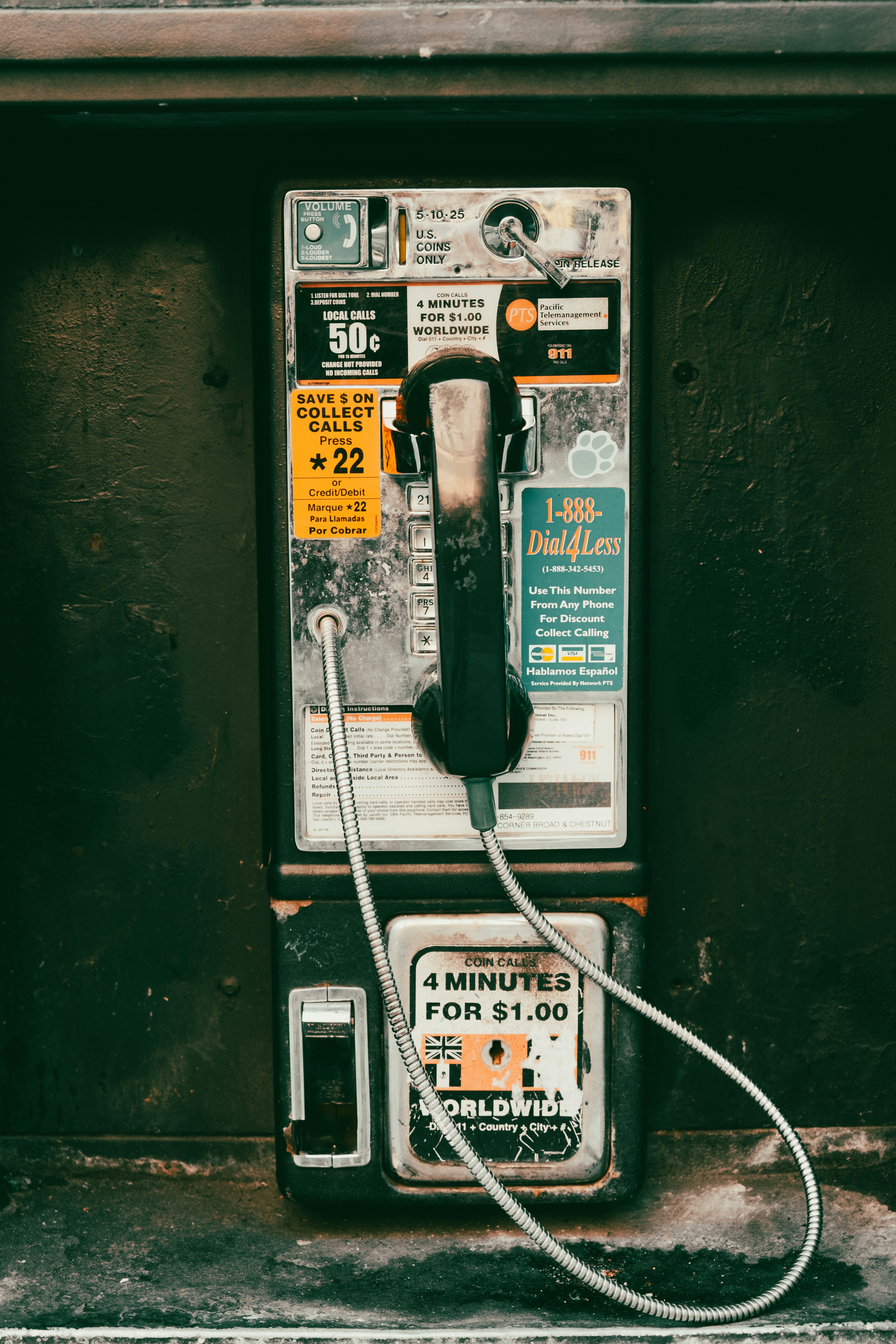 An old fashioned pay phone sitting on the side of a building